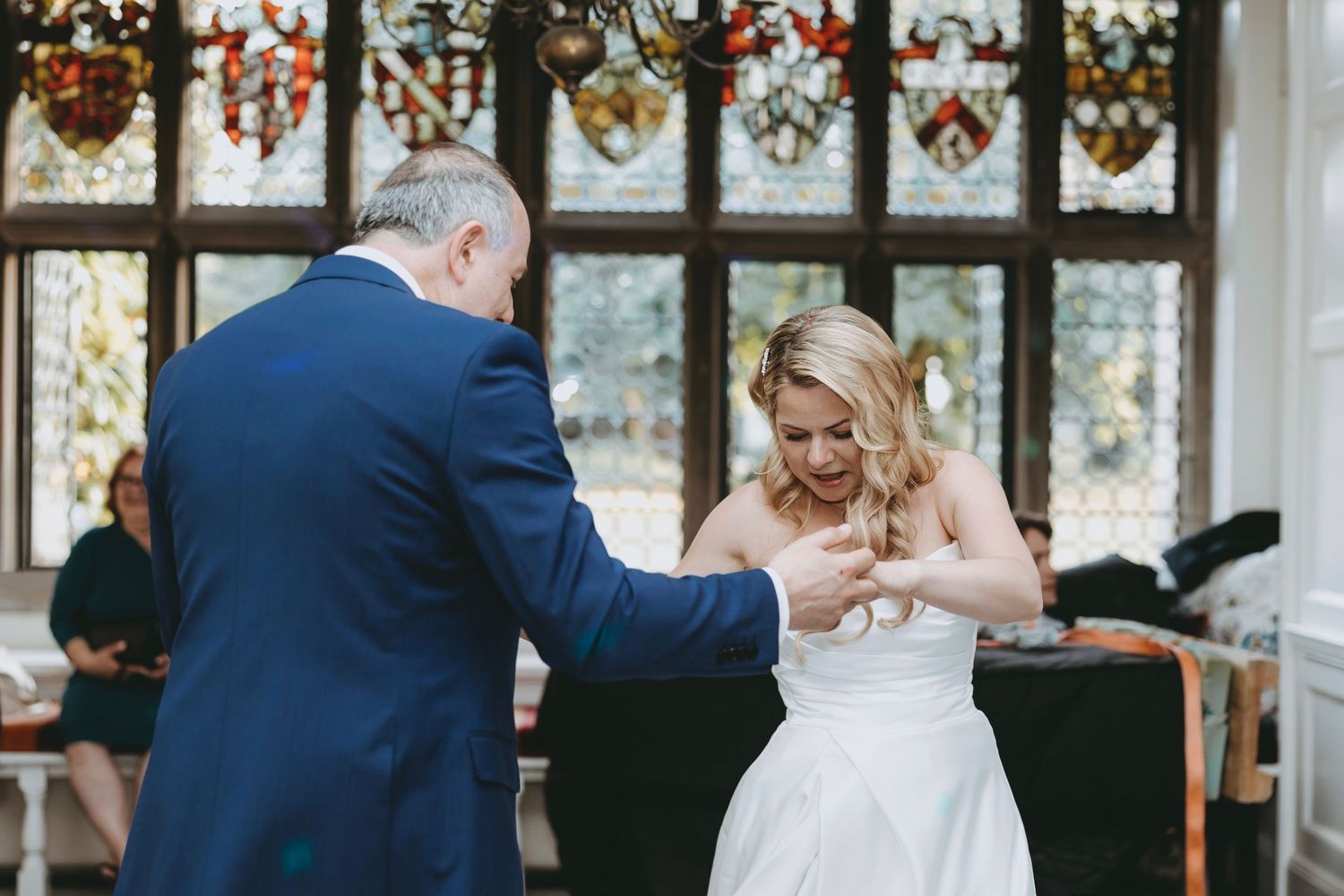 Wedding celebration in an elegant venue with decorative wreaths visible through windows.