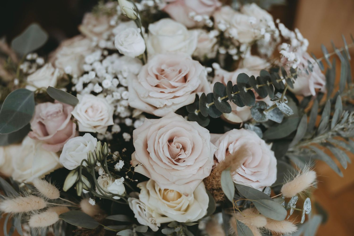 Elegant wedding bouquet featuring blush pink and white roses with delicate greenery.