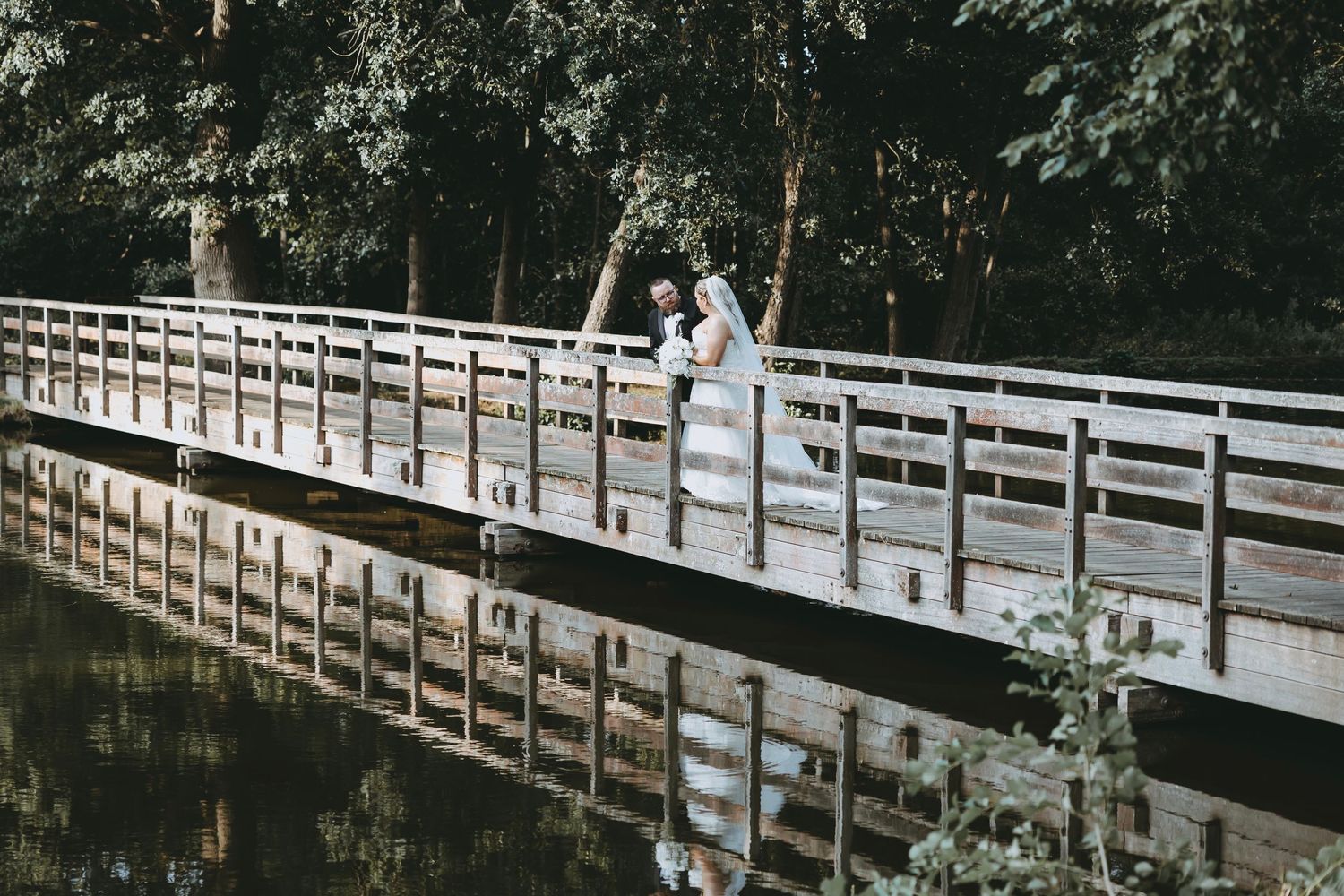Couple shares romantic moment on wooden boardwalk with scenic nature backdrop at Essendon Golf Club, Hertfordshire.