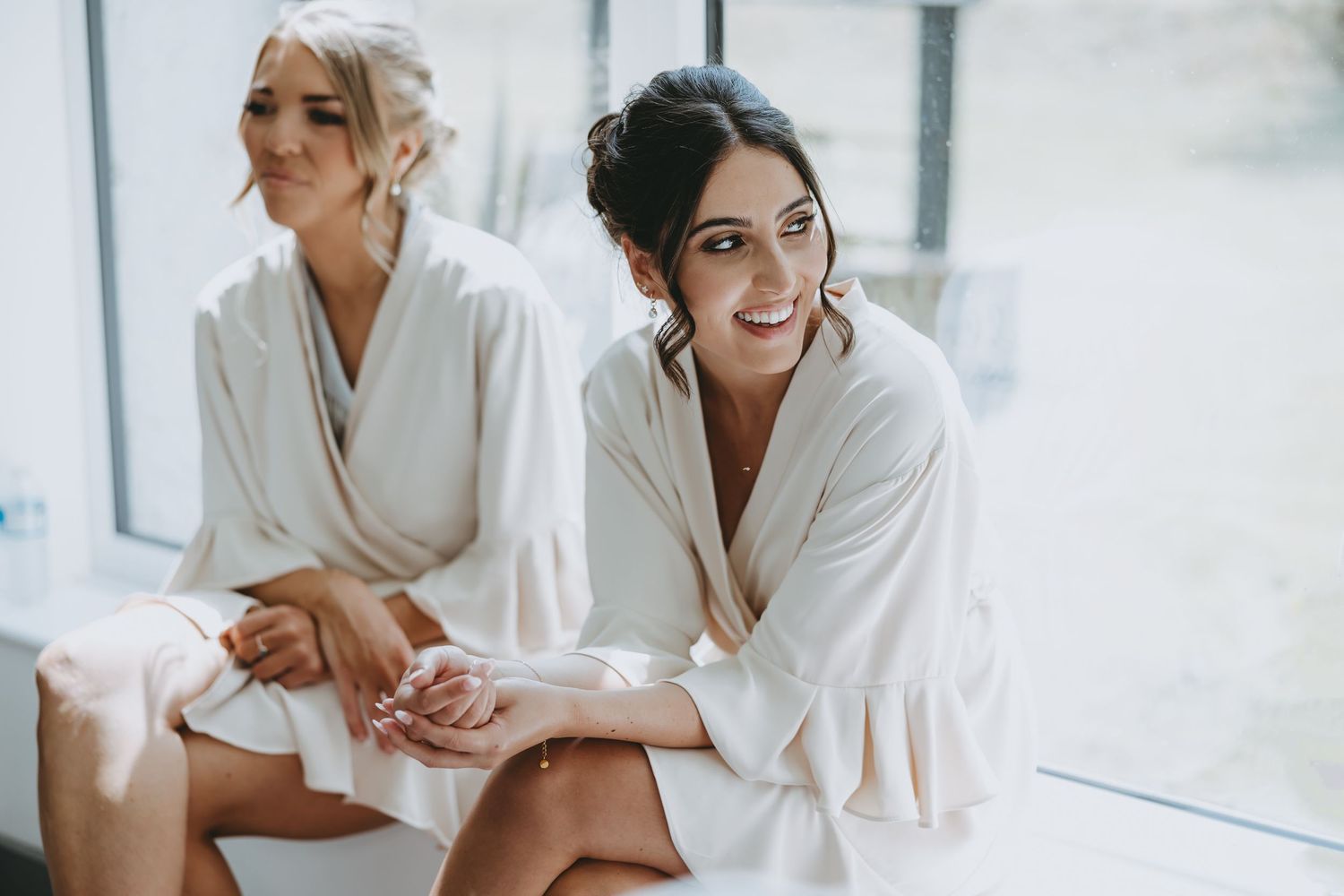 Wedding party members in white robes share a joyful moment while getting ready.