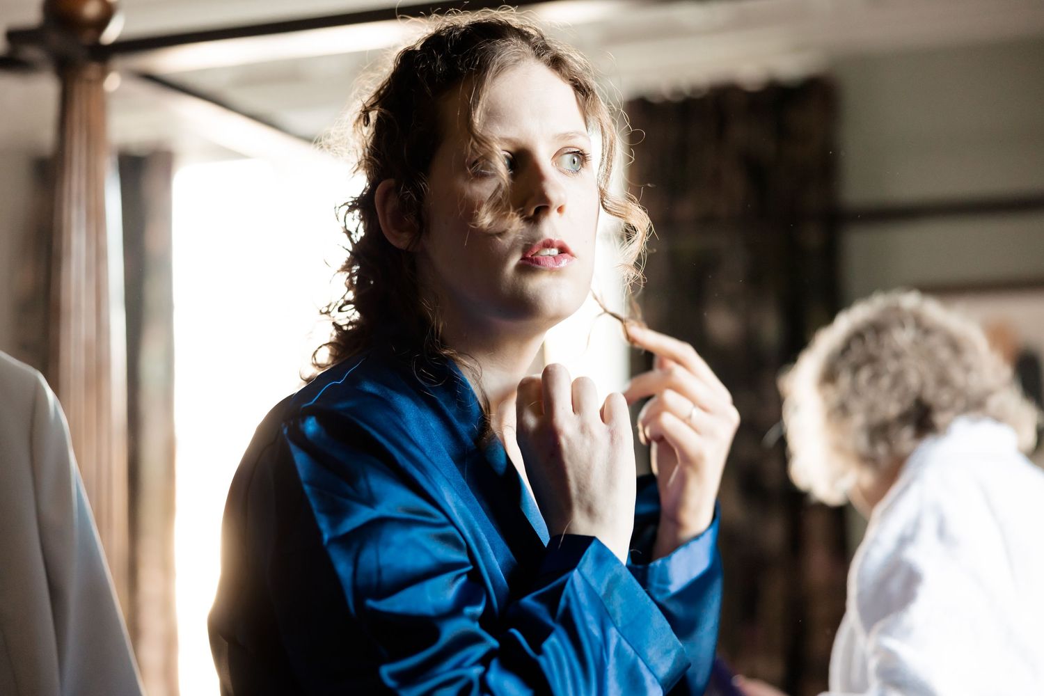 Person in blue jacket stands in dramatic lighting while talking on a mobile phone.