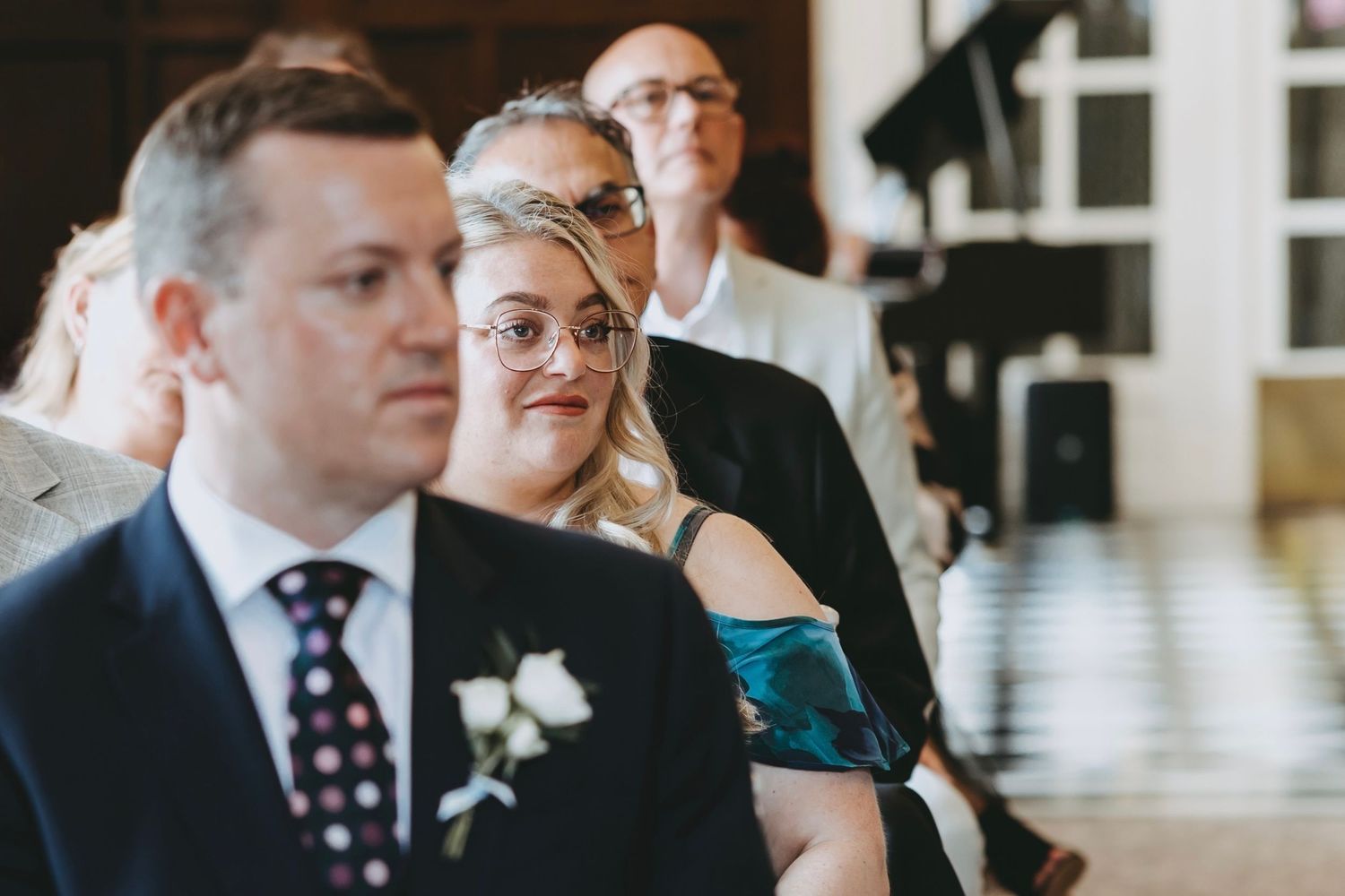 Wedding guests seated in formal attire watching the ceremony in an elegant venue.
