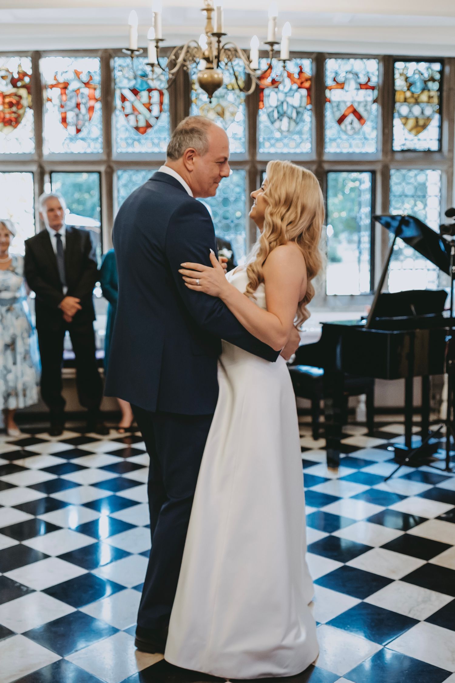 Dancers move gracefully across a geometric floor pattern in an elegant room with decorative windows.