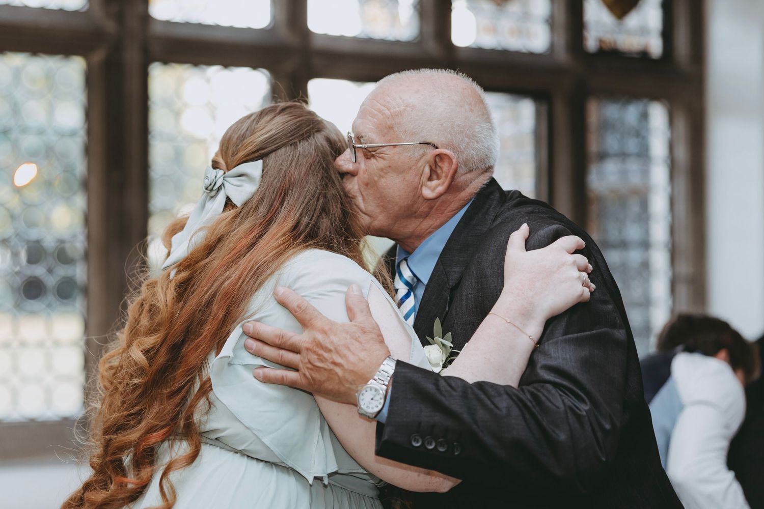 Couples embrace while slow dancing at an elegant indoor wedding celebration.