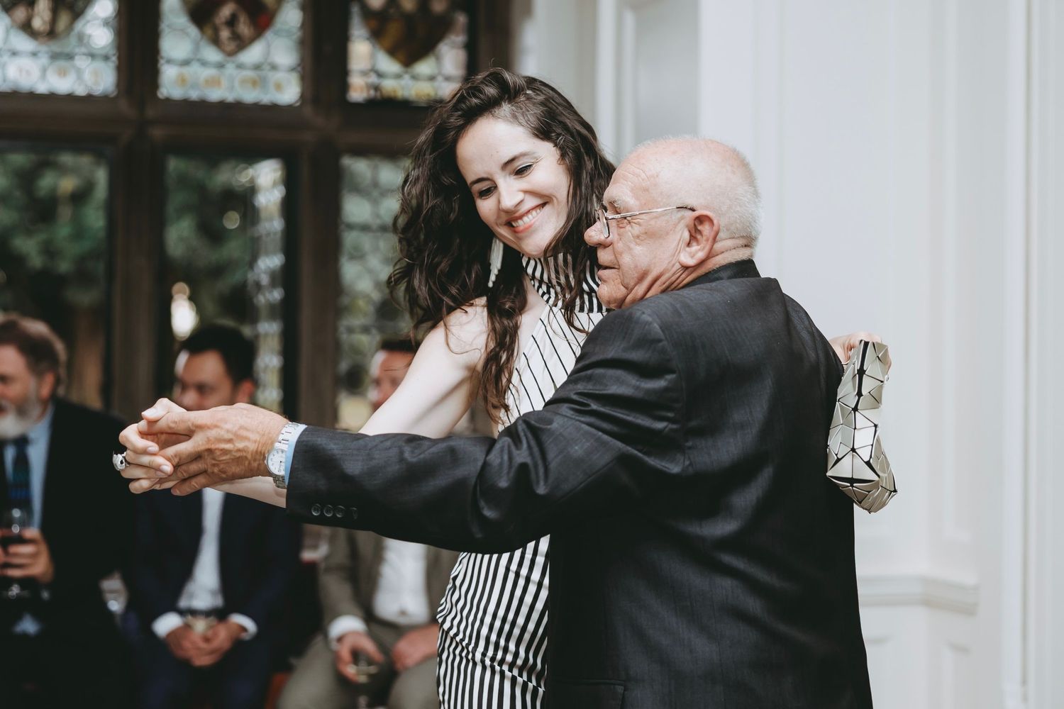 Wedding guests share joyful moments during a dance at an elegant indoor reception.
