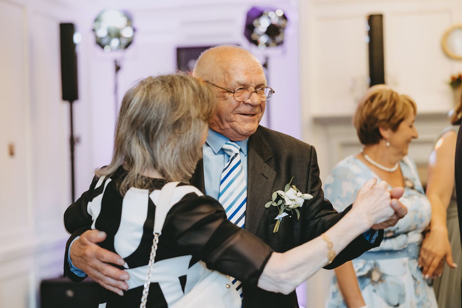Wedding guests dancing and embracing during a festive reception.