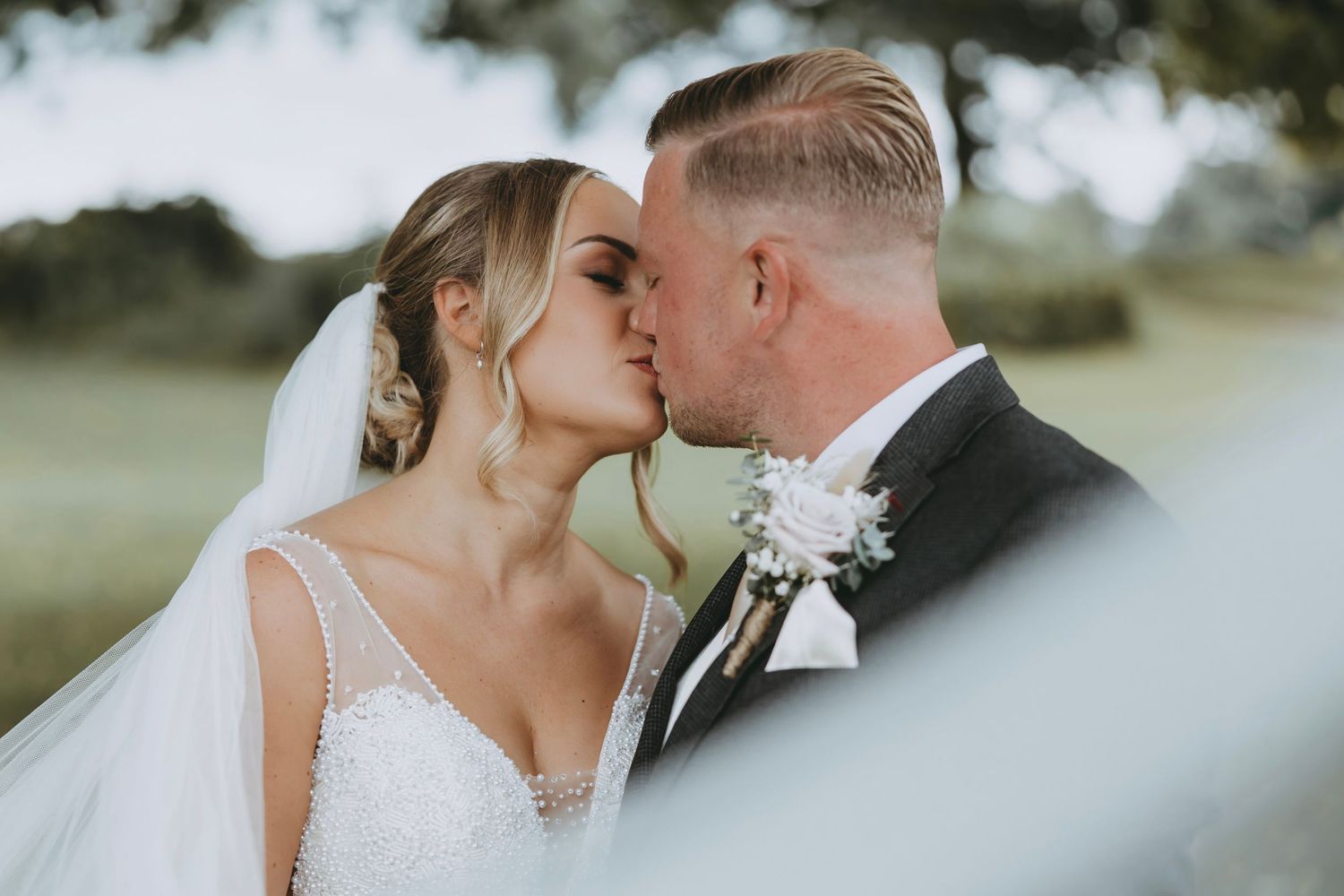 Artistic wedding photo showing couple's tender moment through natural framing.