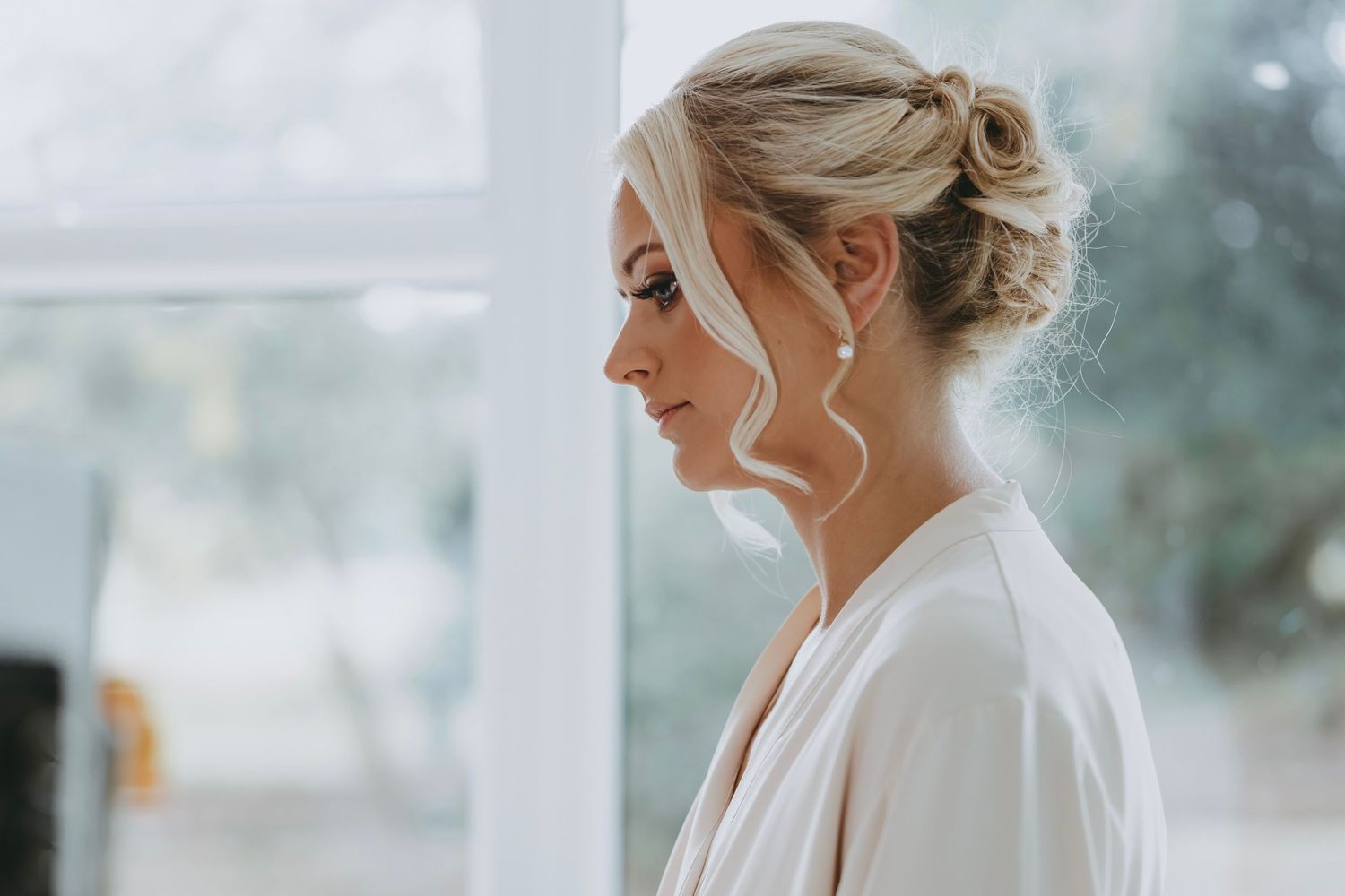 Elegant bridal preparation scene with white robes and natural window lighting.
