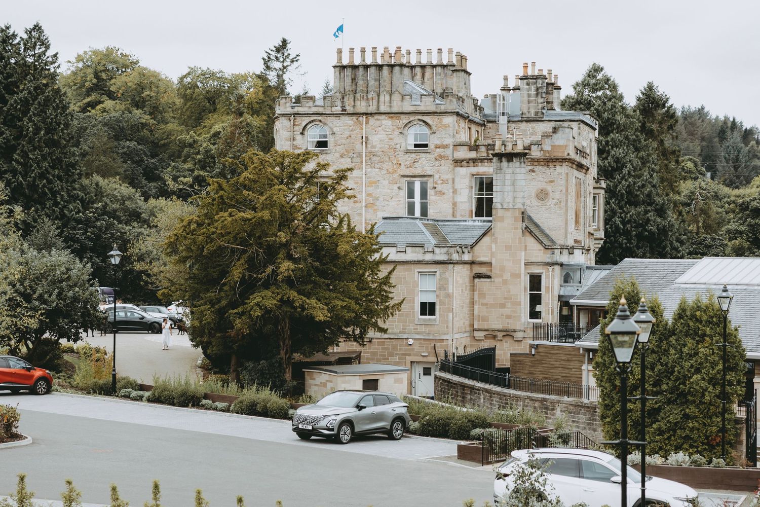 Exterior view of a stone church building with parked cars and trees in the background at Crossbasket Castle, Scotland.