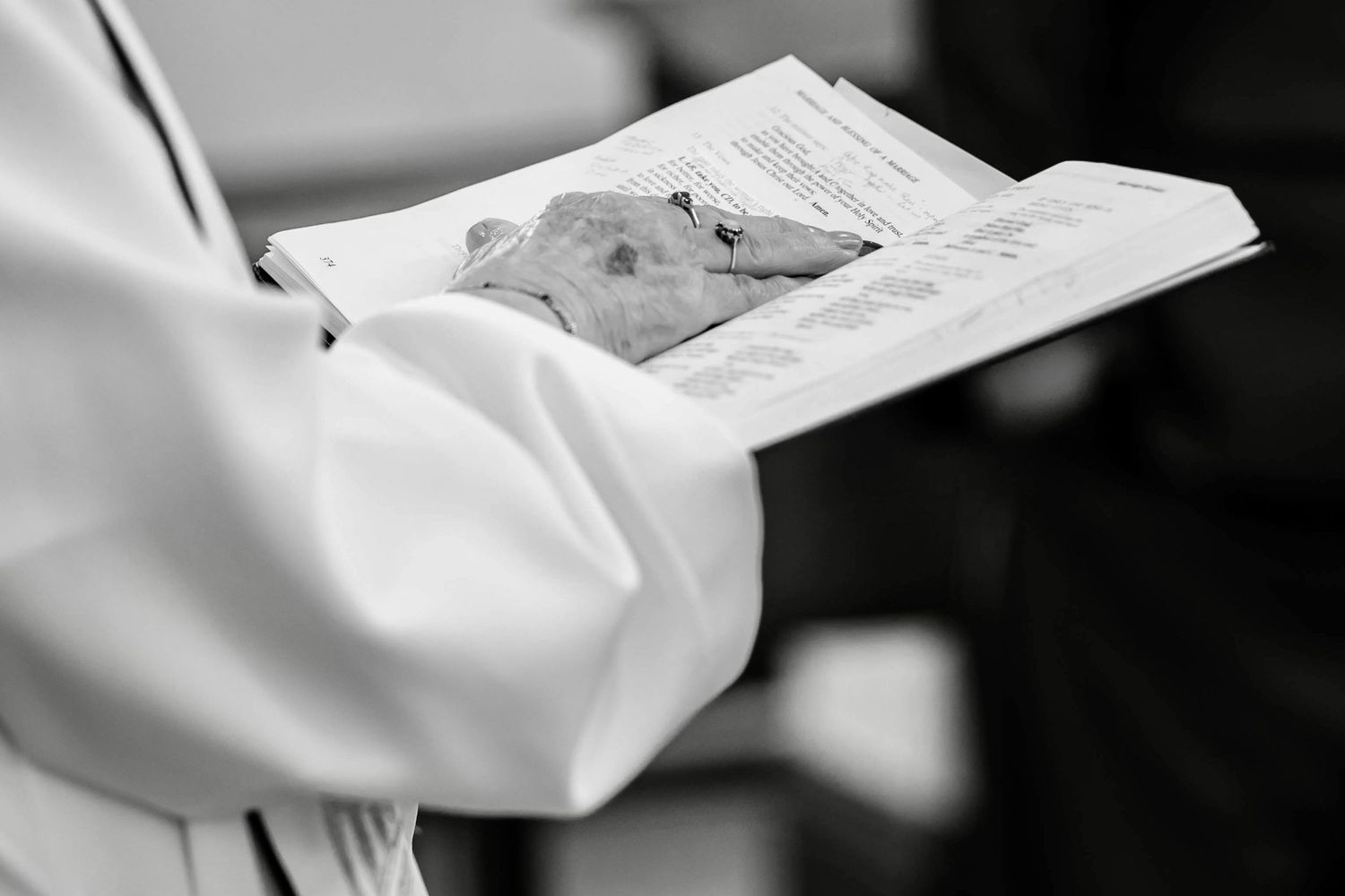 Close-up black and white photo of hands writing on paper with a pen.