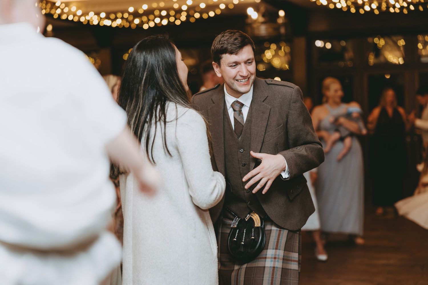 Wedding reception dance floor filled with guests celebrating under twinkling lights.