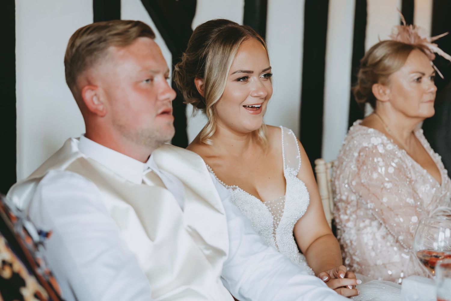 Wedding guests seated at decorated tables during reception speeches.