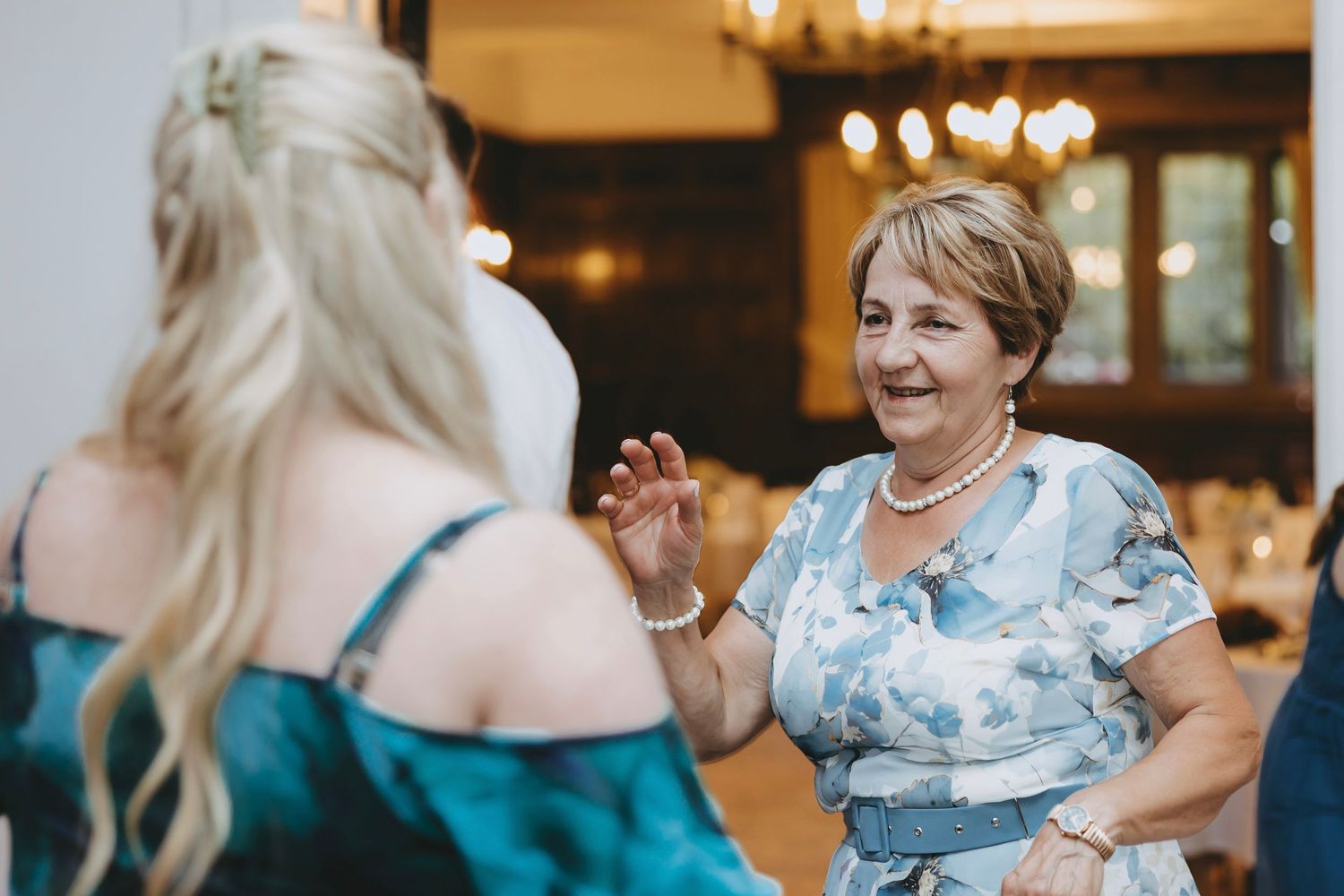 Wedding guests dance joyfully together on a dance floor at an indoor reception.