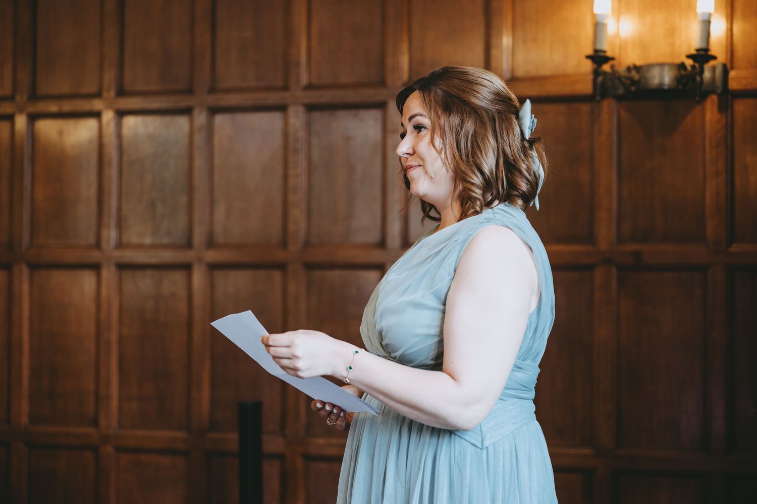 Wood-paneled ceremony space with chandelier lighting and wedding guests in formal attire.