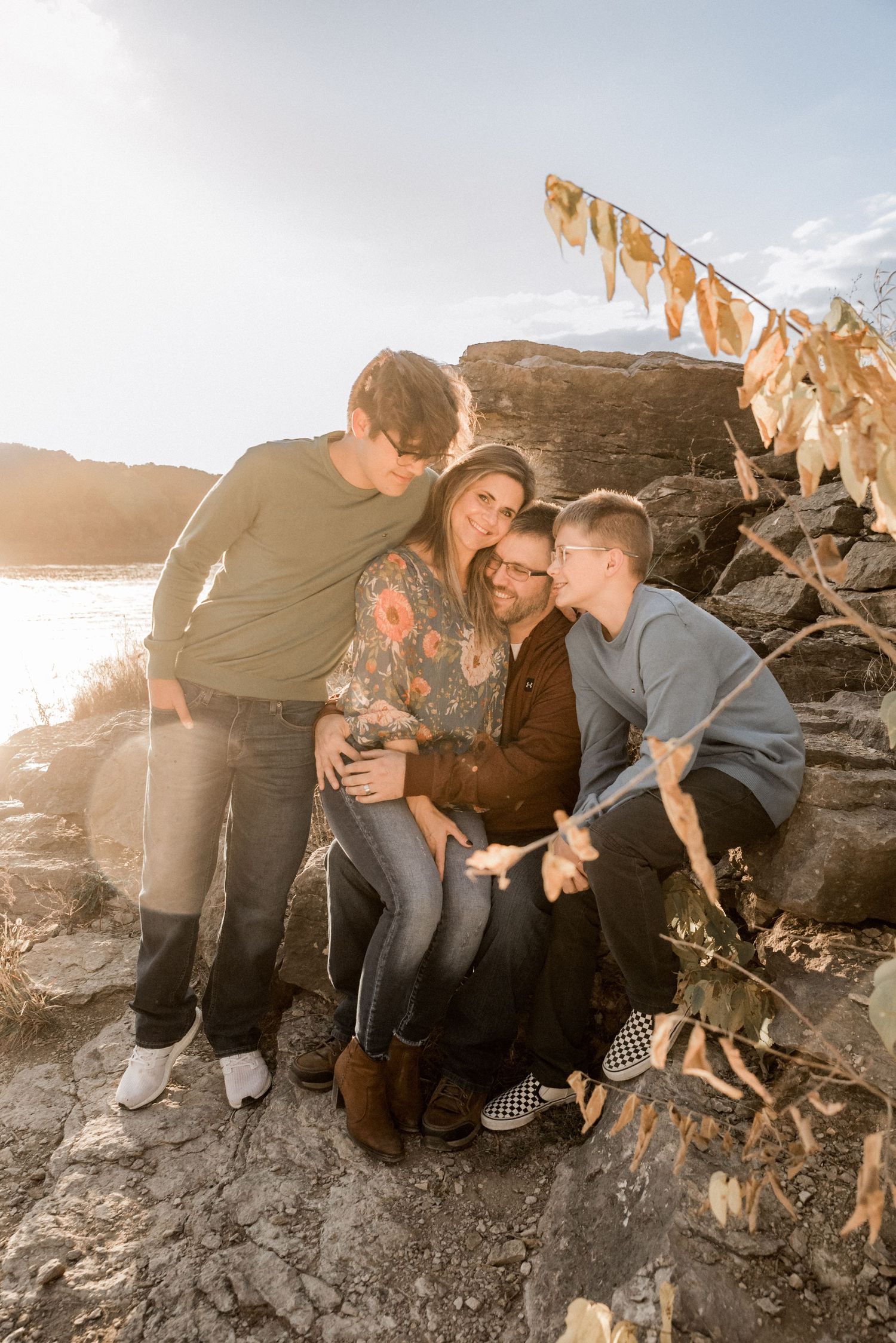 Casual family photo session on rocky landscape with warm sunset lighting and natural interactions.