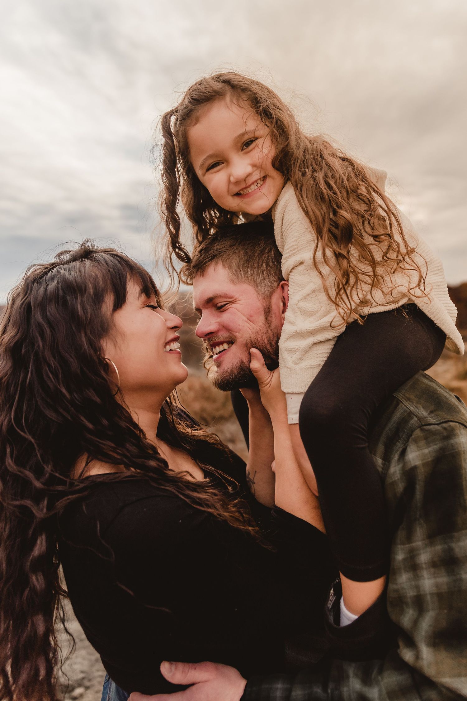 Family sharing intimate moments and laughter together against a cloudy sky.