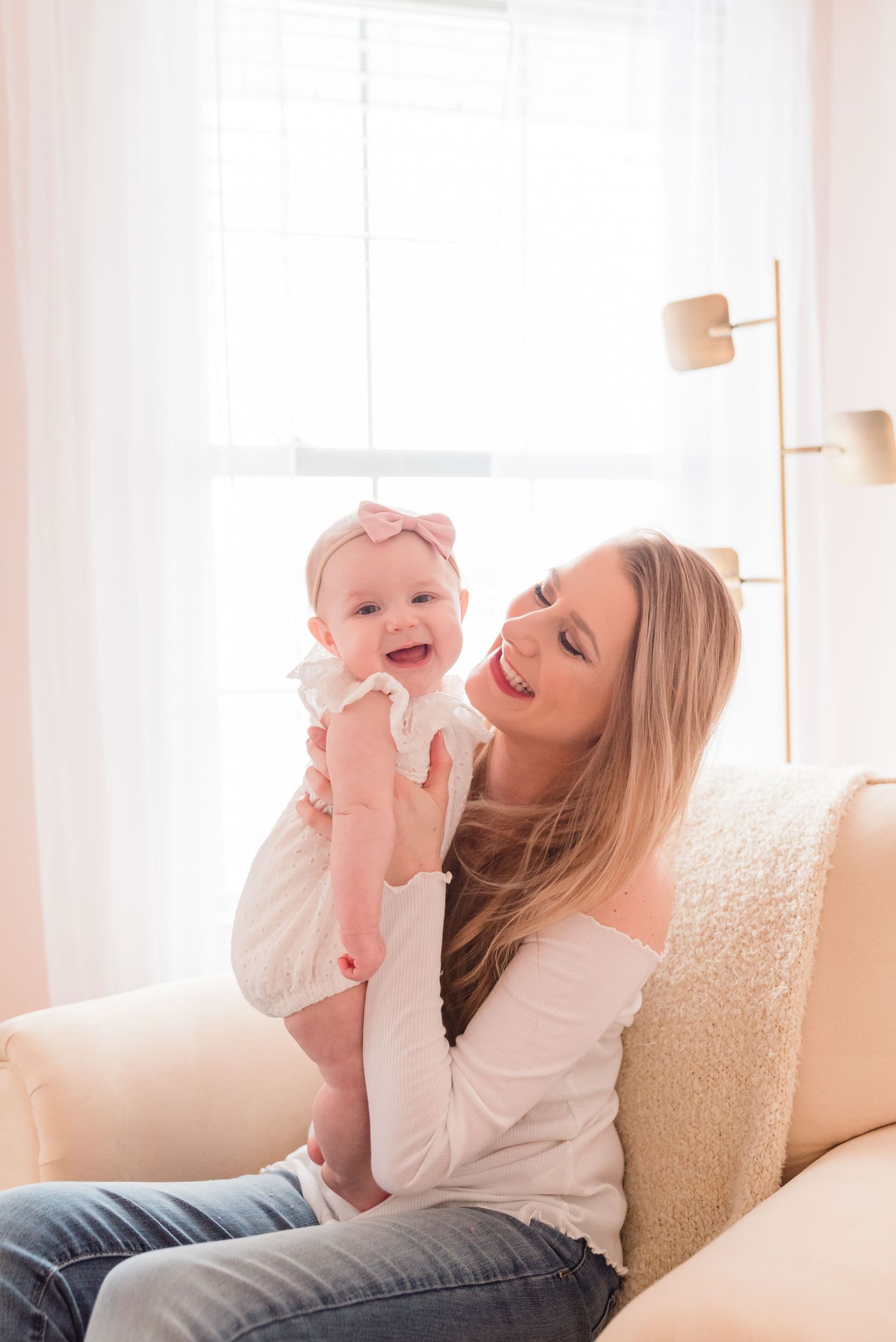 Joyful playtime moment on a cozy white couch with a baby.