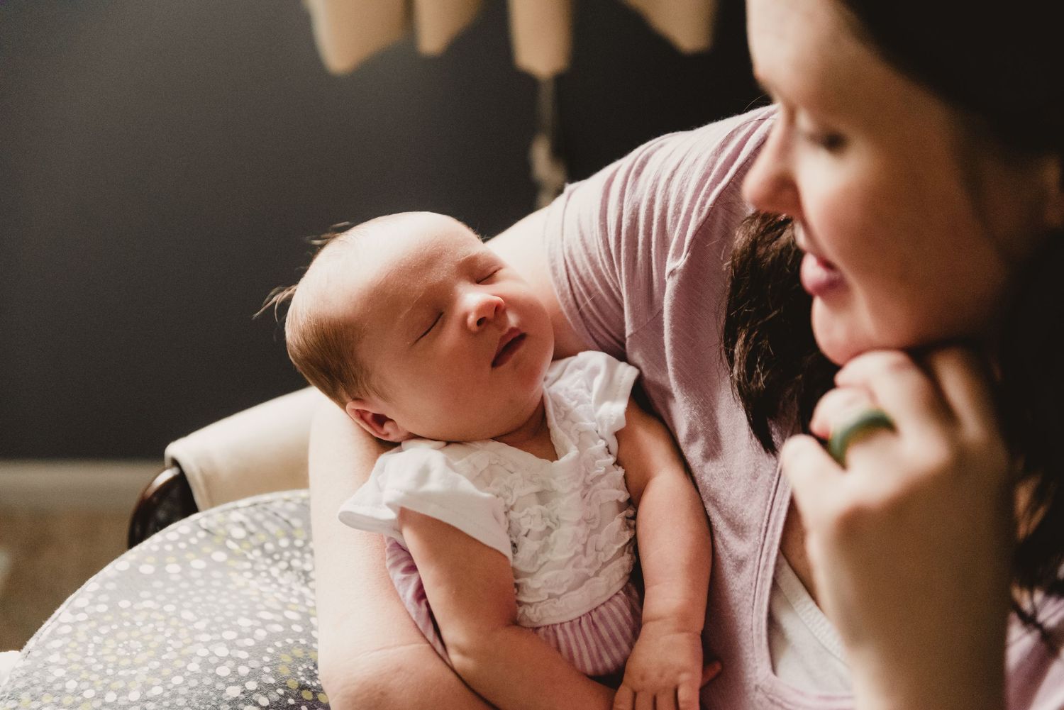 Intimate newborn photography session with baby on textured blanket in warm lighting.