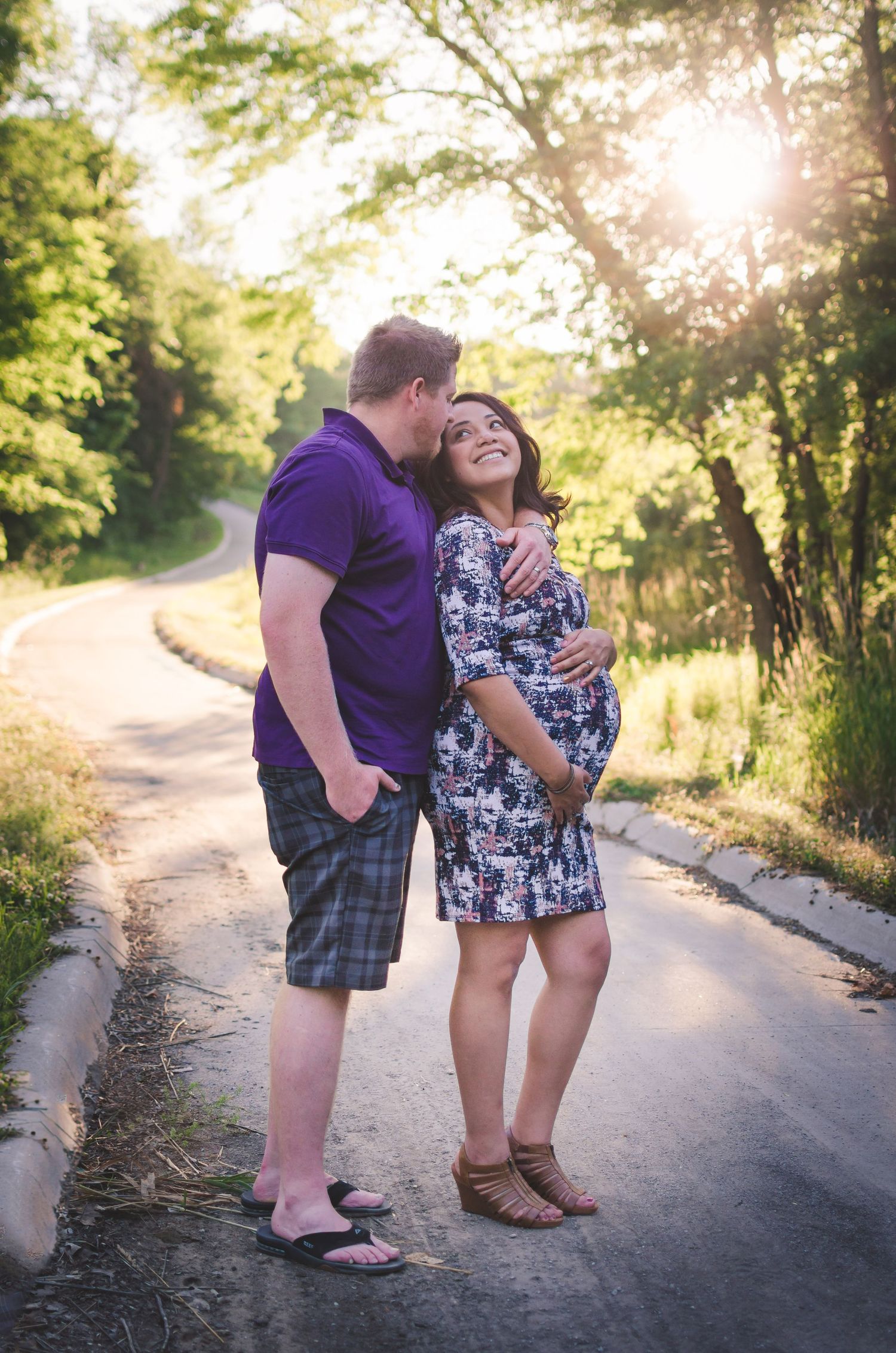 Couple sharing playful moments on a sunlit country path surrounded by greenery.