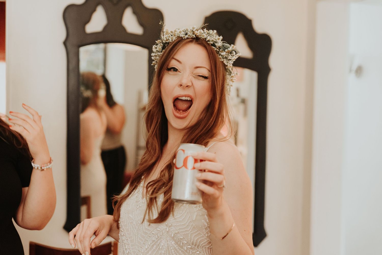 Bride wearing a floral crown celebrating with friends in warm-toned indoor shots.