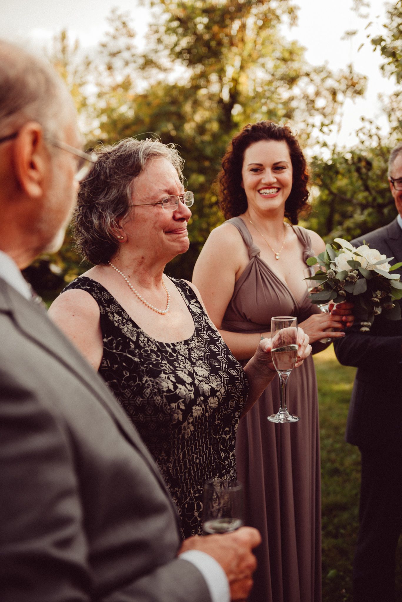 Wedding guests enjoying drinks and conversation at an outdoor reception in elegant evening attire.