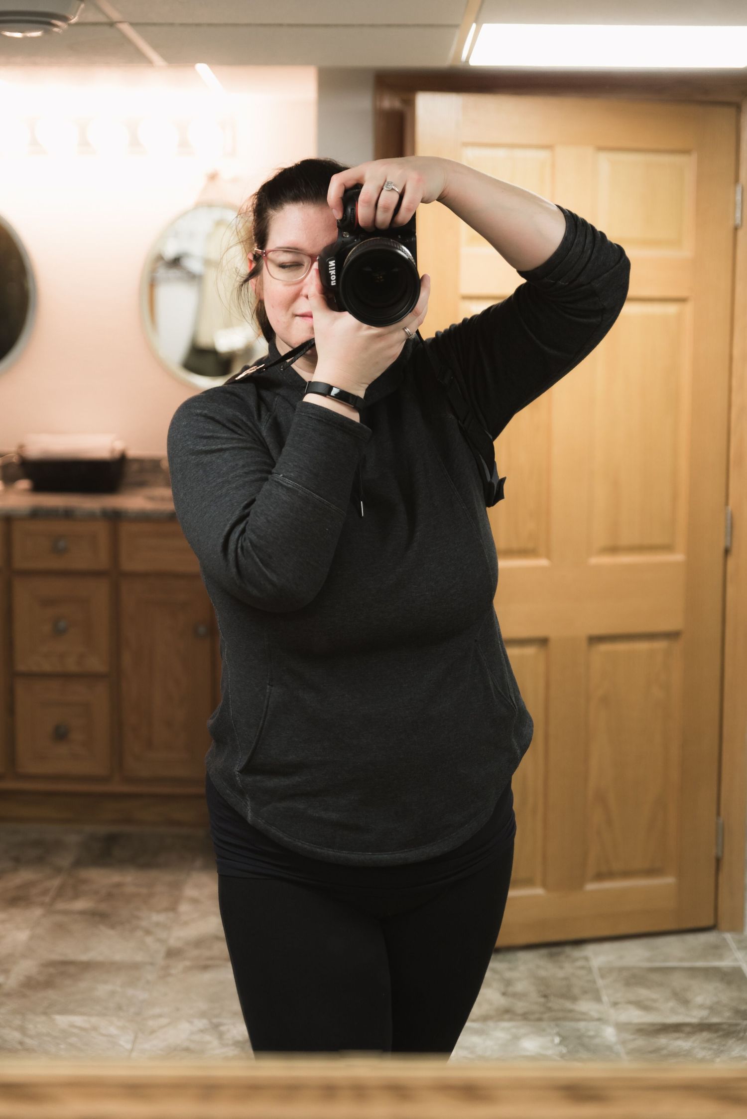 Photographer in black sweater taking pictures in indoor setting.