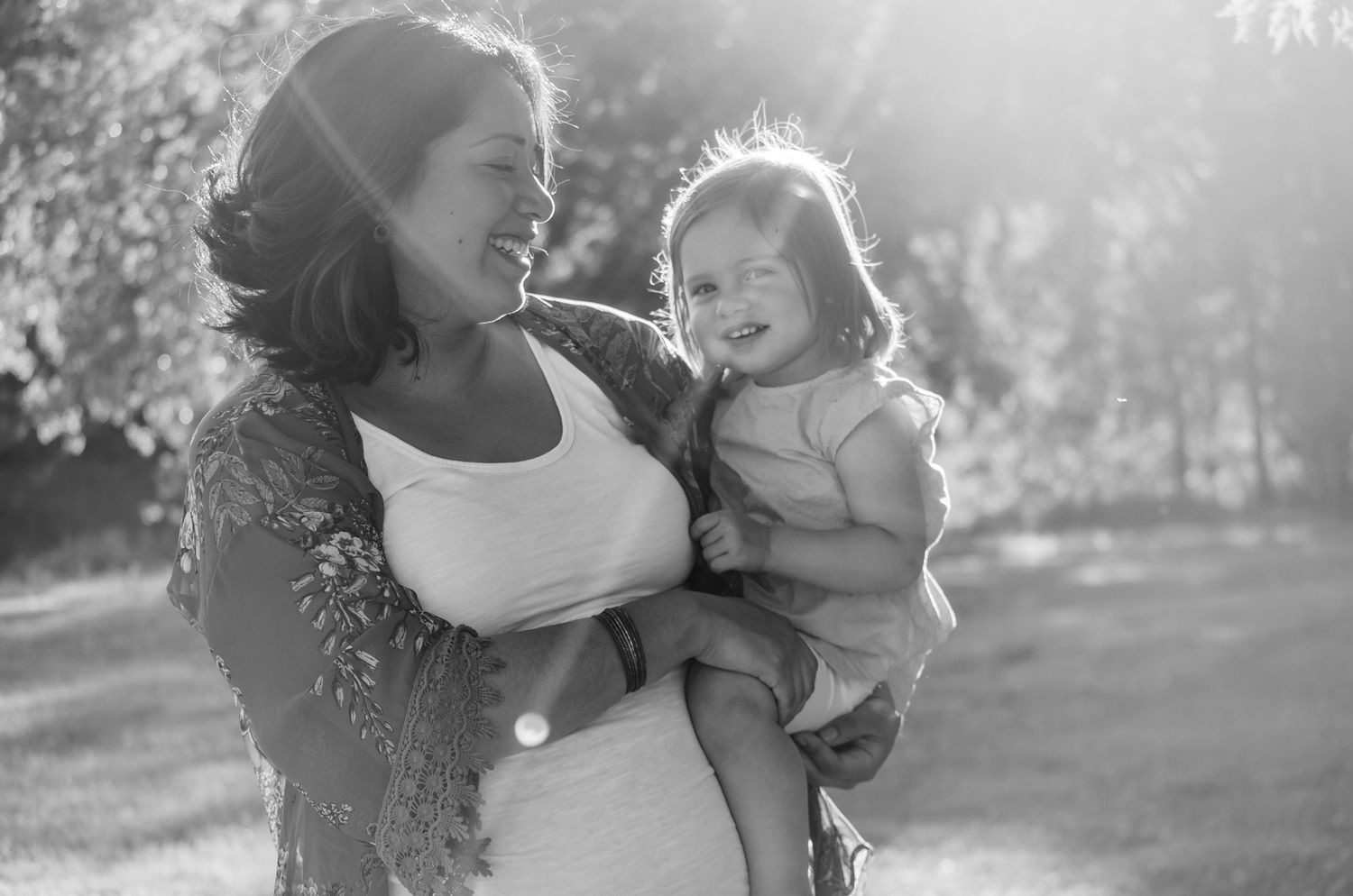 Backlit outdoor portrait session with sunlight filtering through trees.