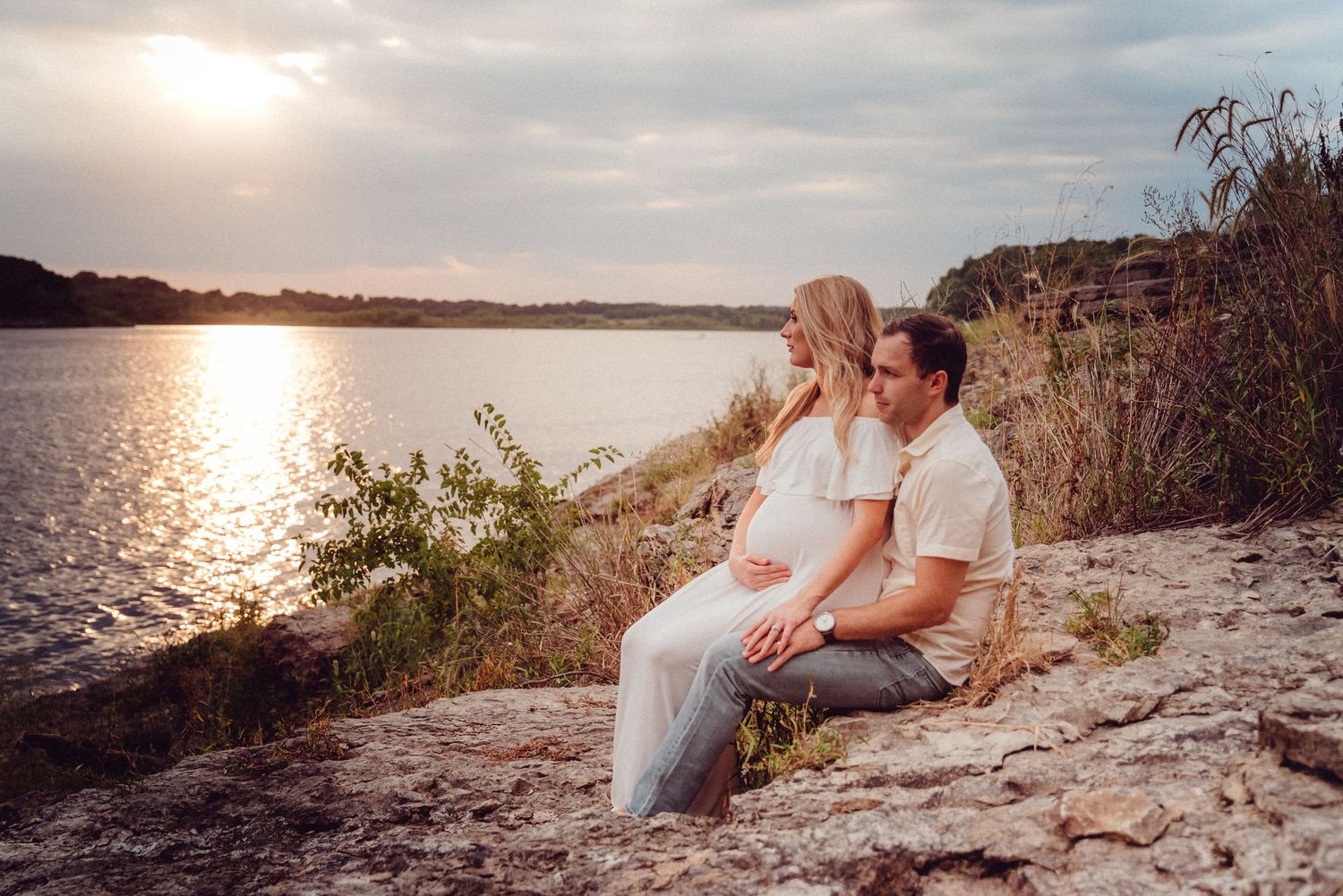 Romantic sunset photoshoot along a rocky coastal shoreline.