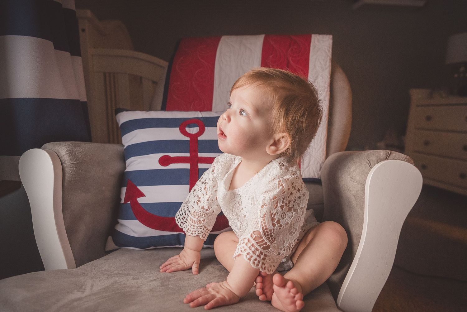 Baby resting on striped cushions in a cozy armchair setting.