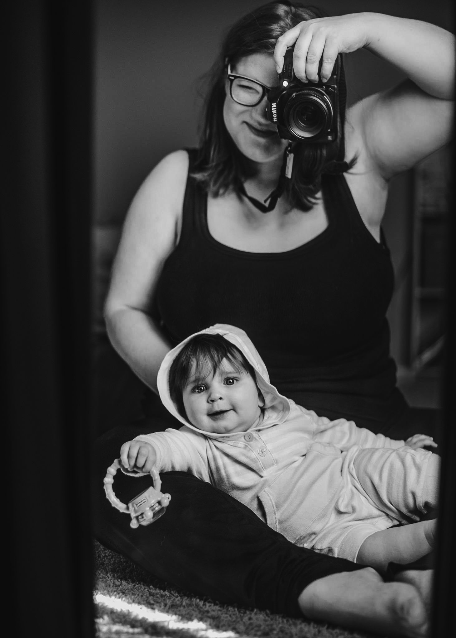 Black and white photo of baby in white outfit during lifestyle photography session.
