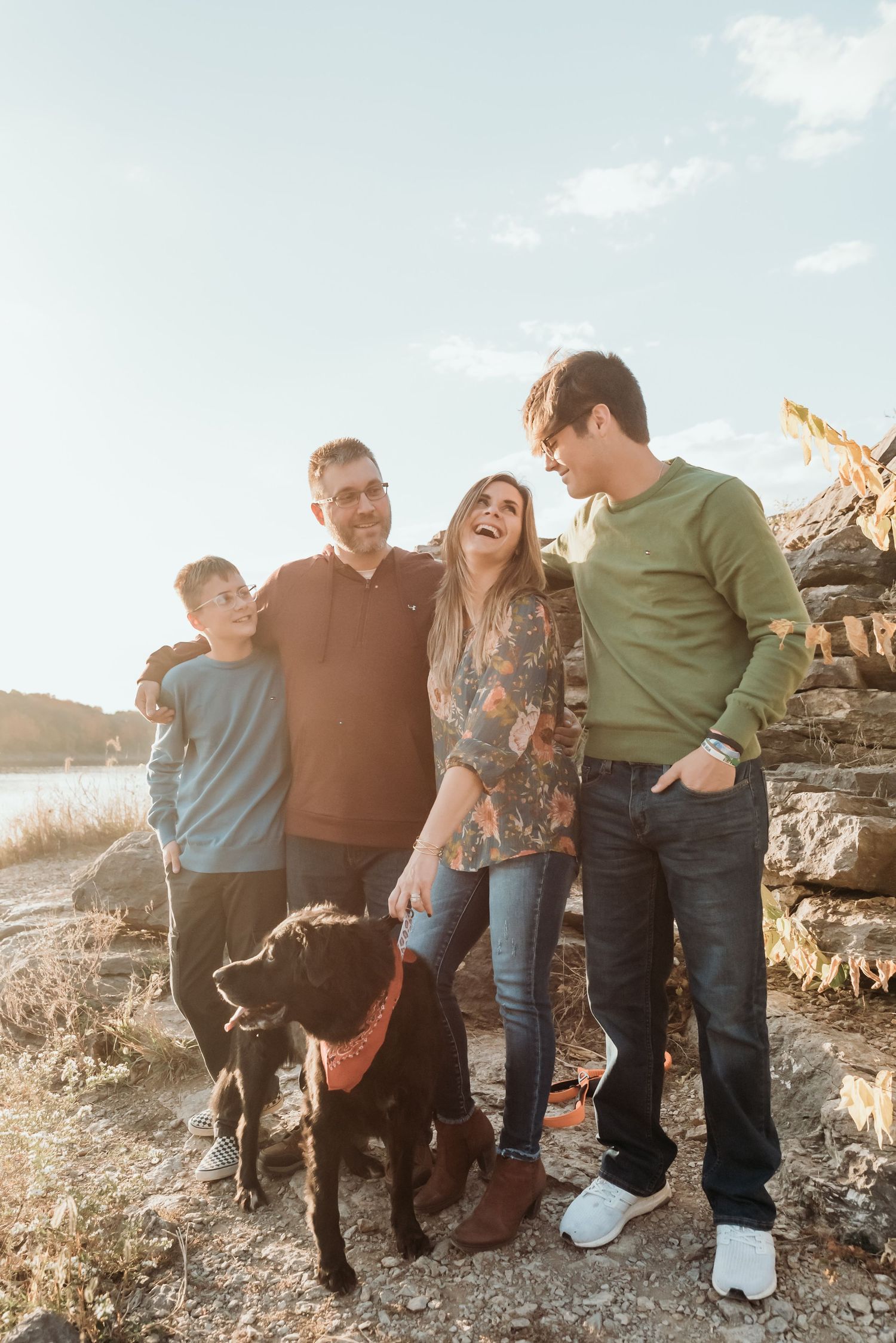 Family sitting together on rocky terrain during golden hour with casual poses and genuine smiles.