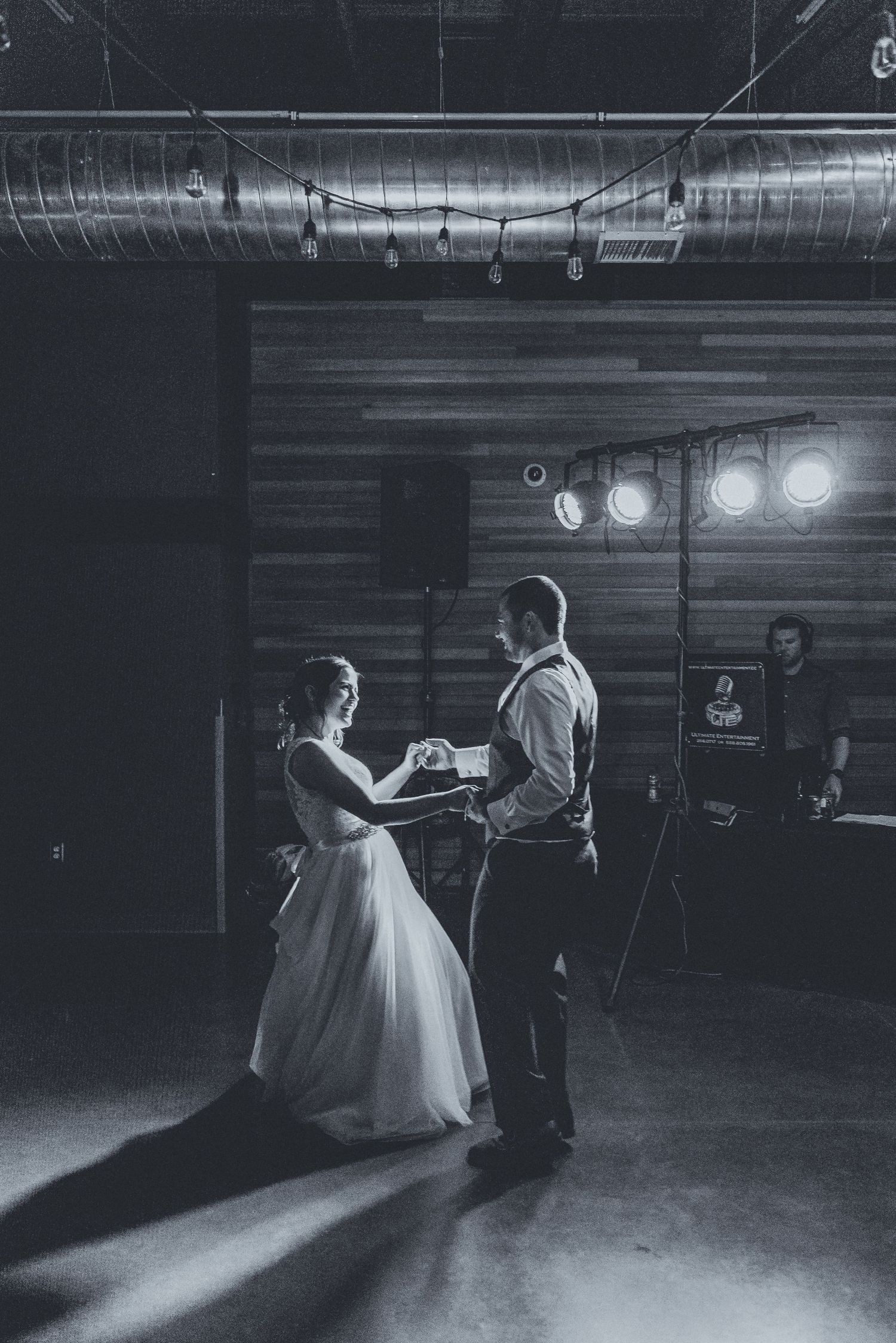 Black and white photos of a couple dancing in a dimly lit venue with dramatic lighting.