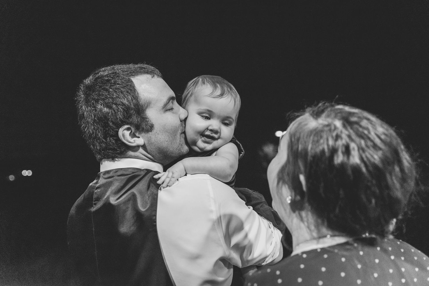 Black and white candid moments from a wedding celebration showing joyful interactions.