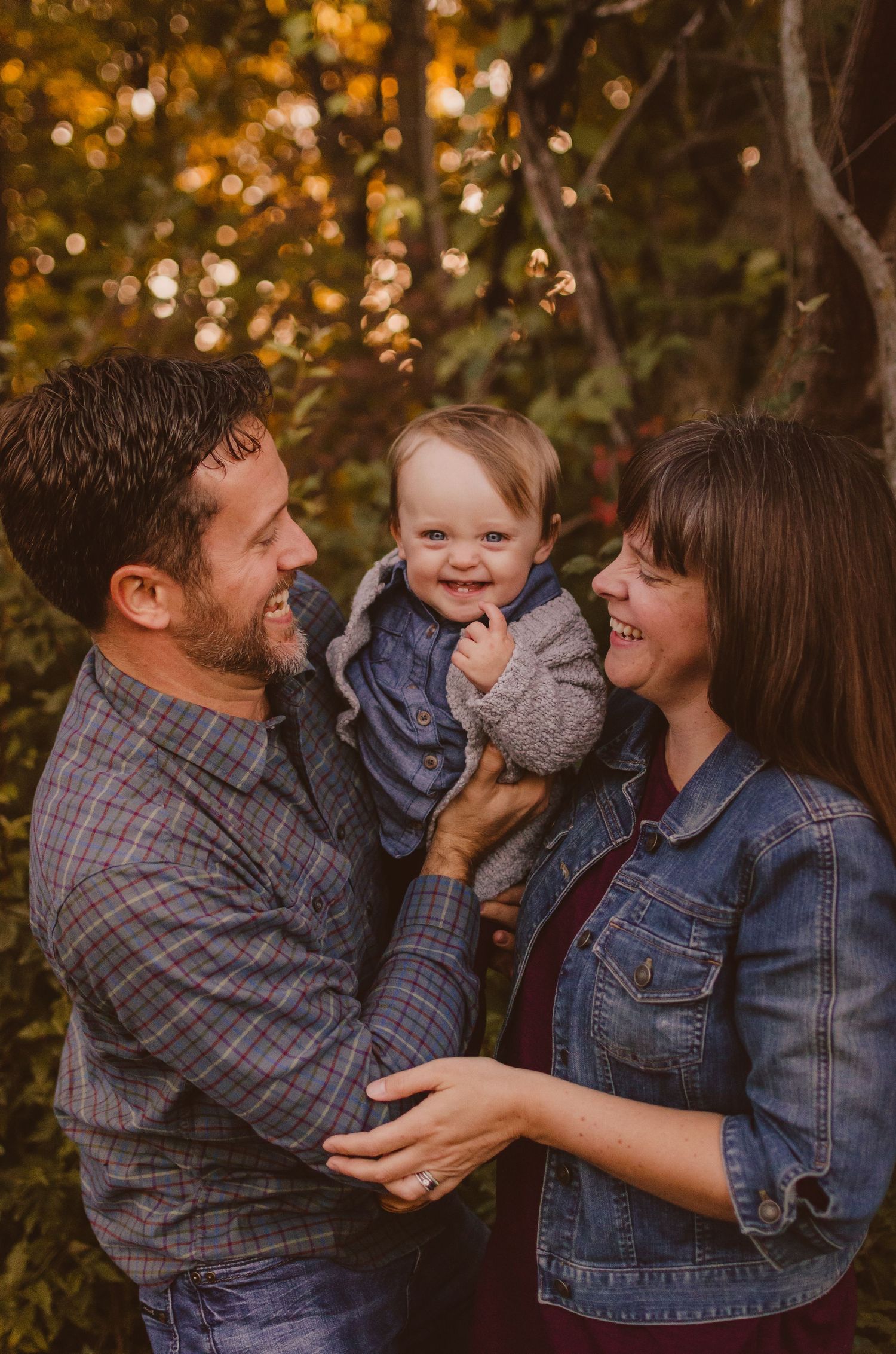 Family sharing playful moment together against autumn foliage background.