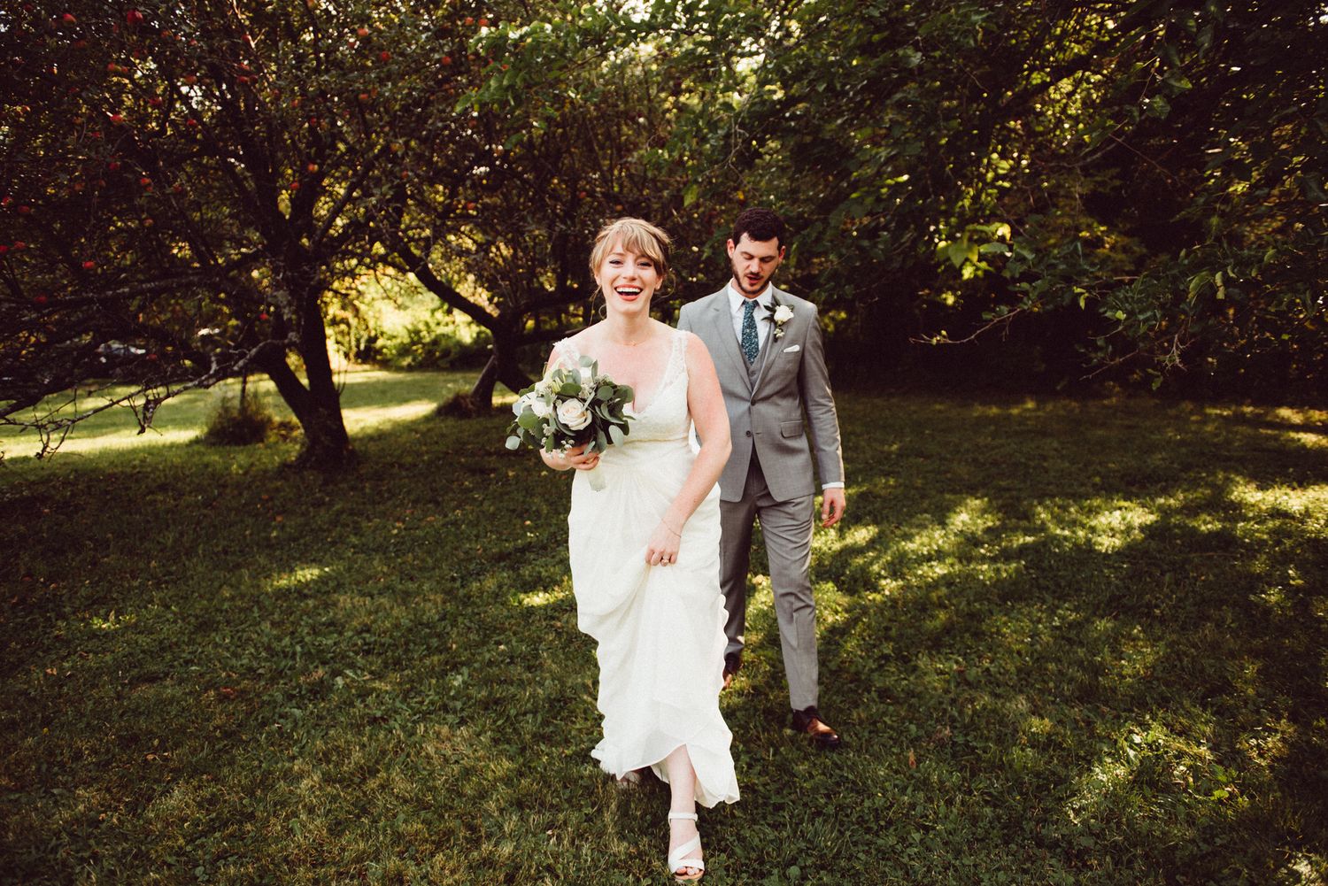 Wedding party celebrates outdoors in a sunlit garden setting with joyful expressions and formal attire.