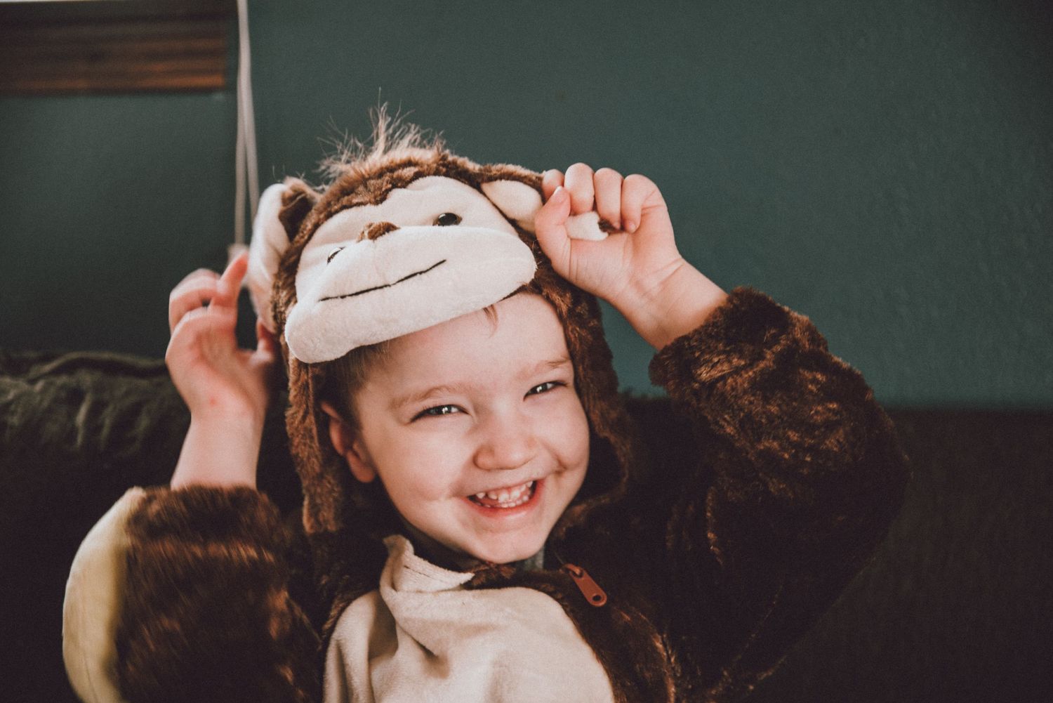 Child wearing white headband playing indoors with joyful expression.