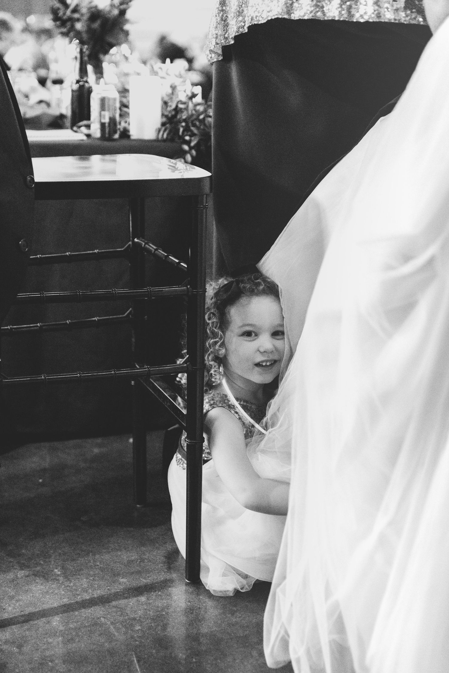 Black and white candid photos capturing playful interactions with a wedding dress.