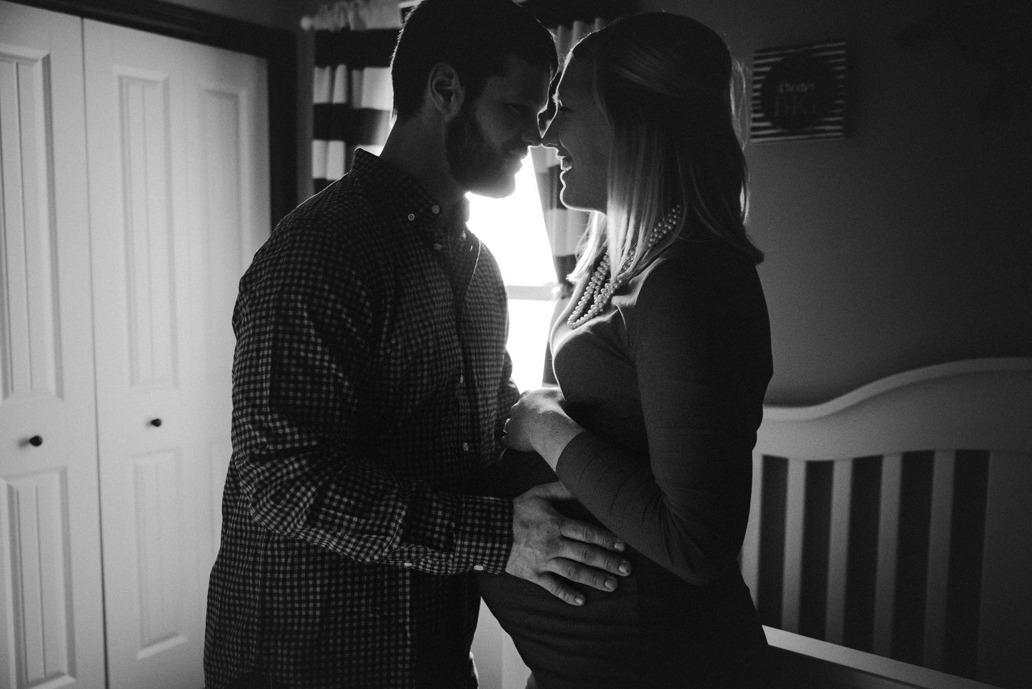 Intimate black and white maternity photos in a nursery setting.