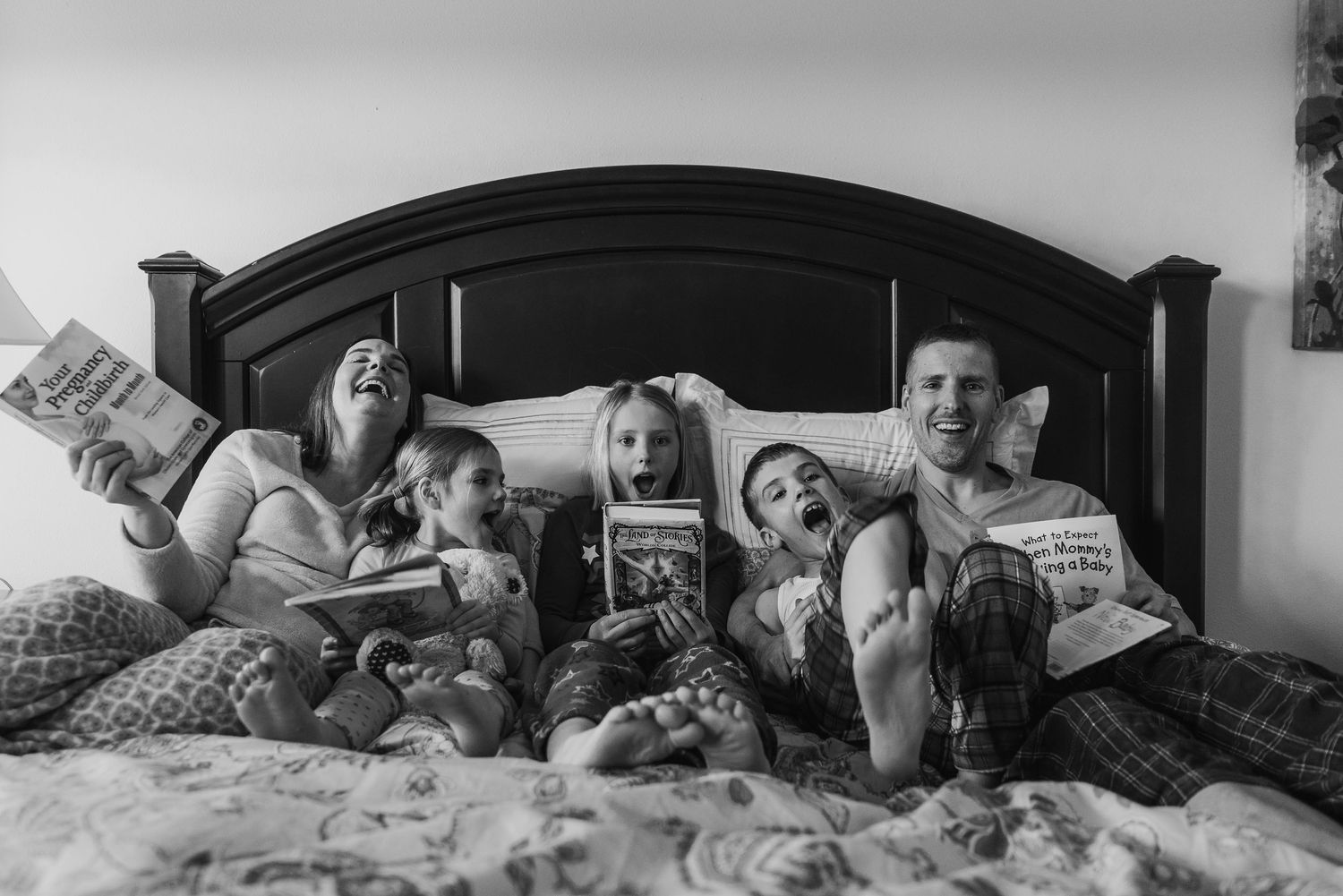 People relaxing together on a bed while reading books and magazines.