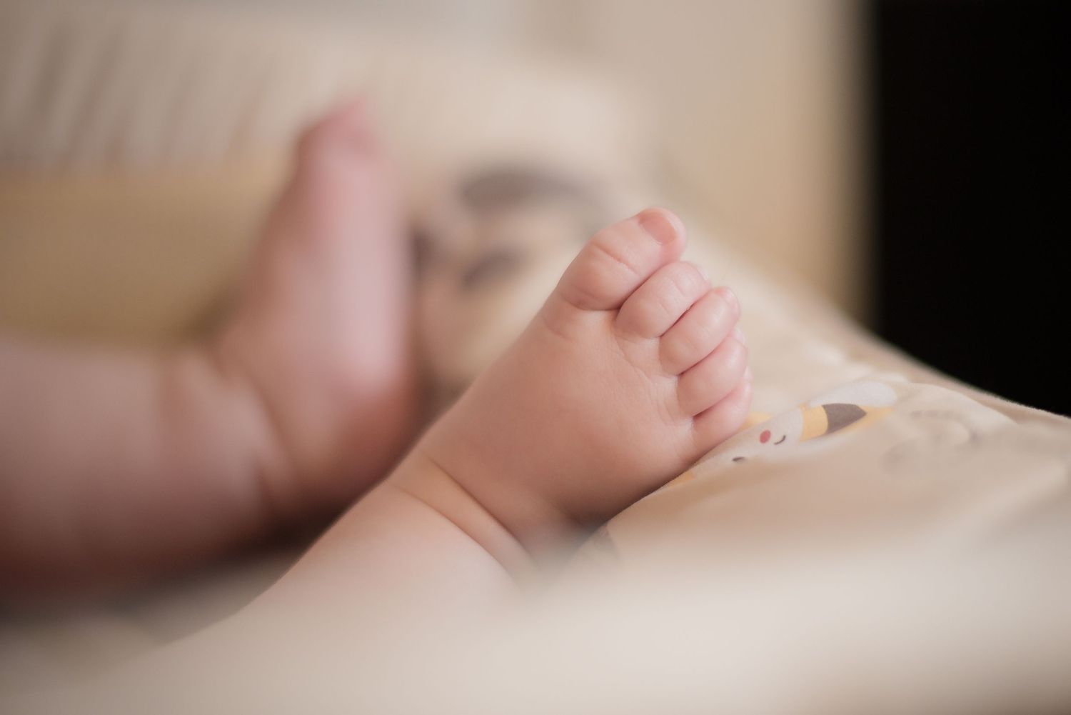 Close-up of tiny newborn baby feet against soft white fabric.