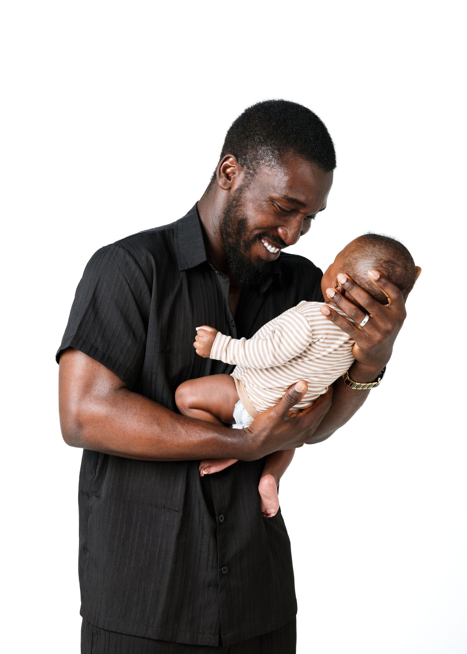 black man with his baby photoshoot in front of a white background in a studio in winnipeg for a family portrait session.