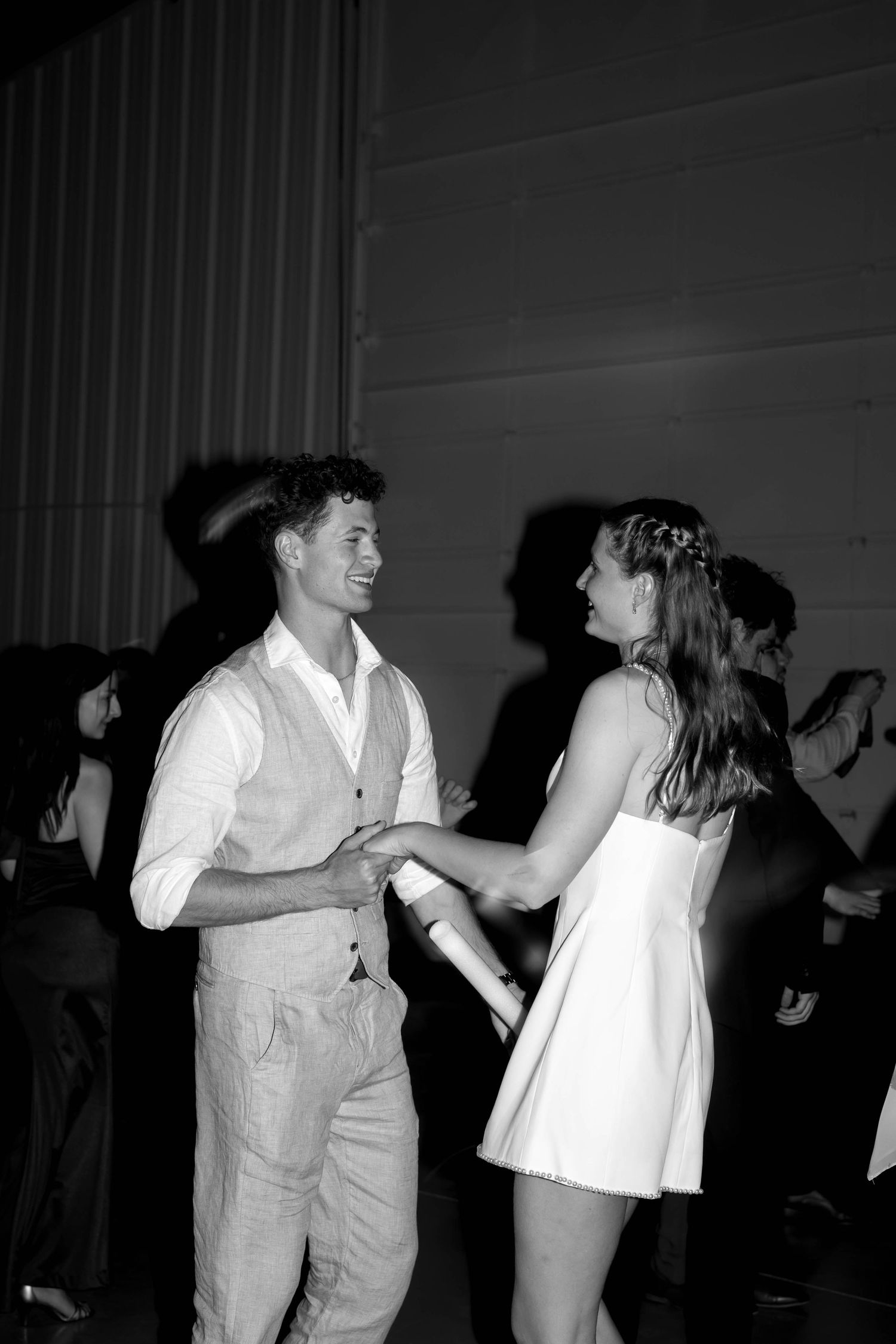 Black and white photo of couple dancing together joyfully at a wedding reception.