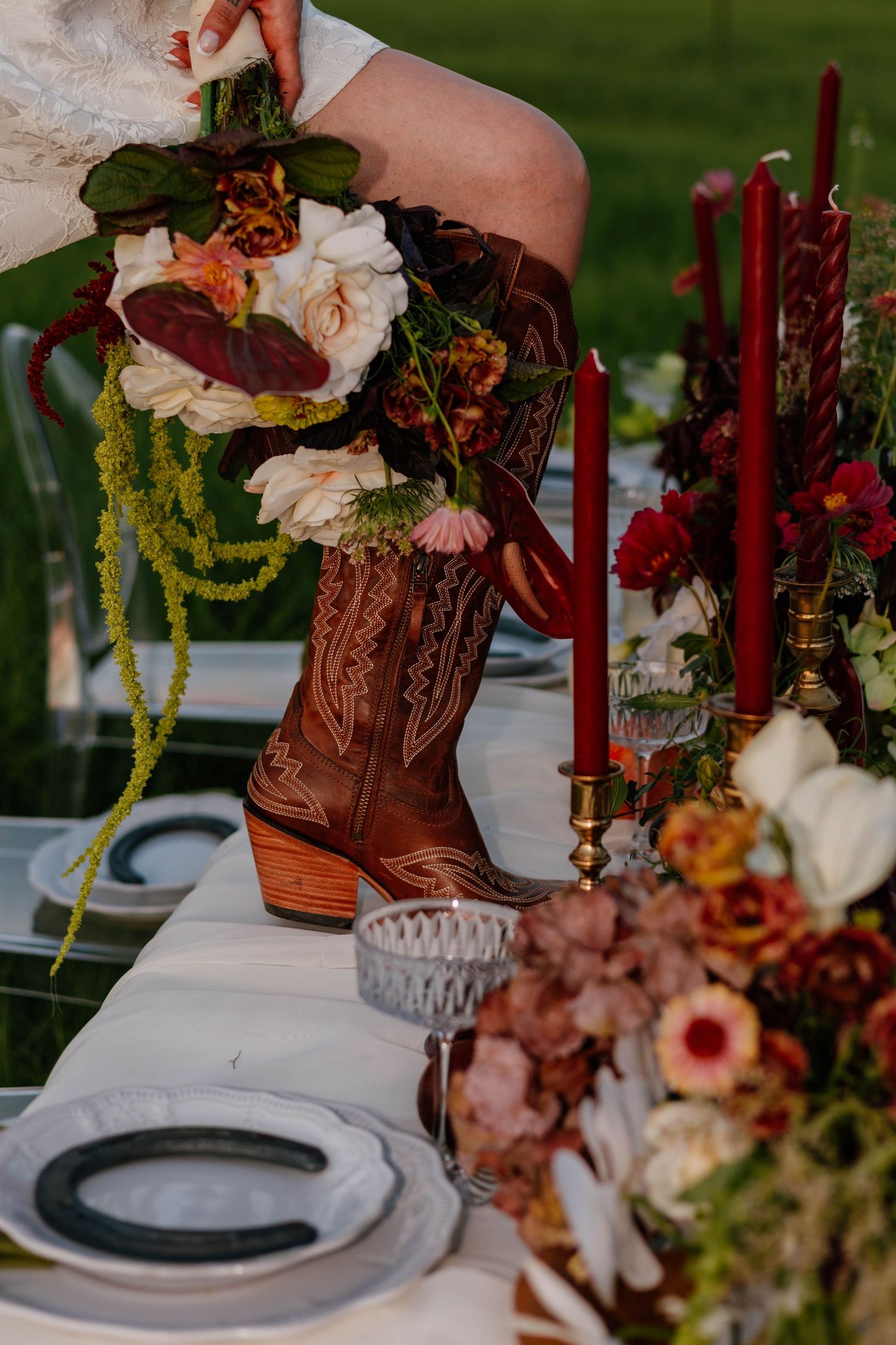 Cowboy boot with floral bouquet displayed on elegantly decorated wedding reception table.