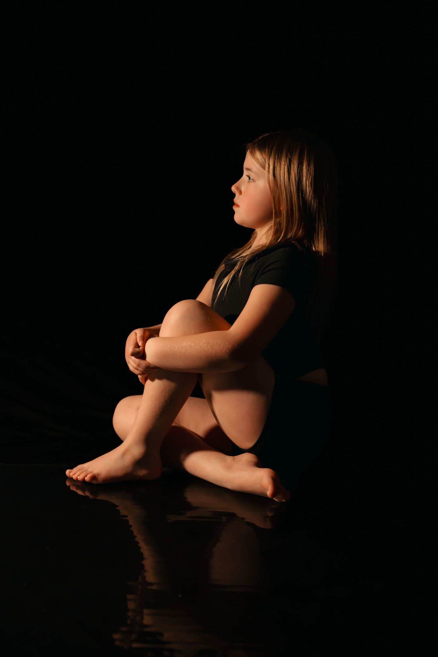 Artistic black and white photo series showing silhouette of child sitting in contemplative poses against dark background.