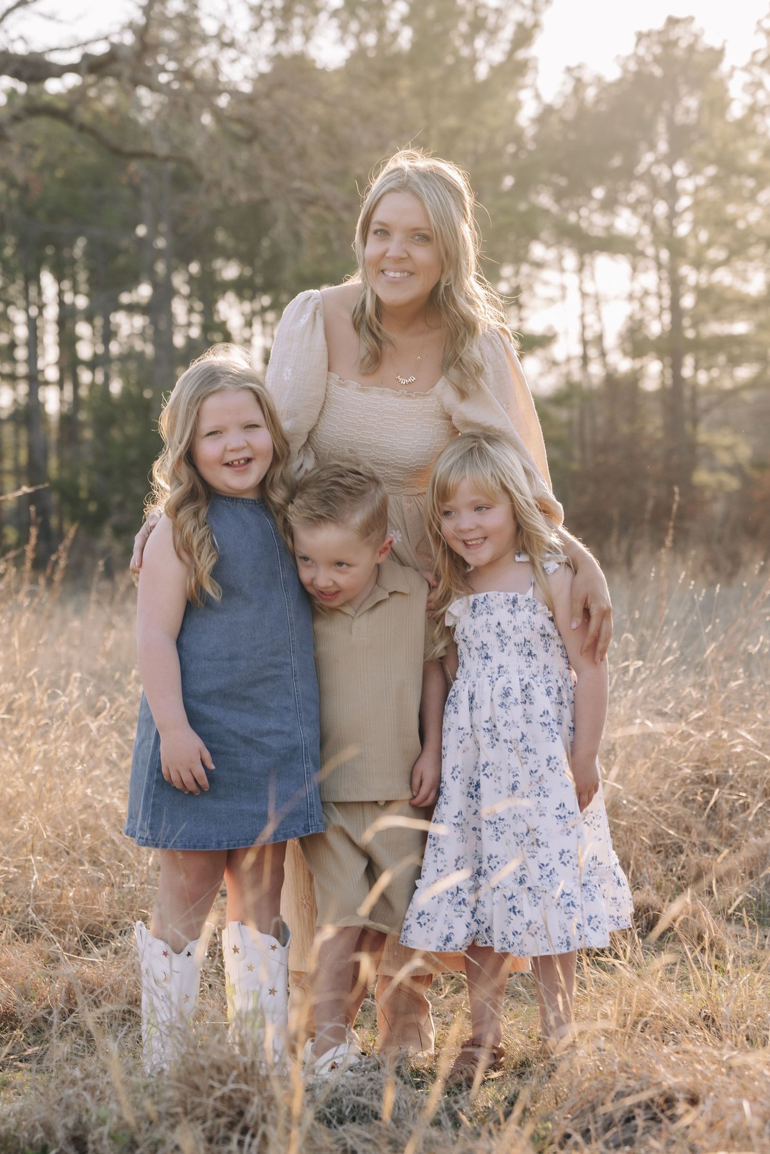 Family portrait series in a sunlit field with tall grass and trees during golden hour.