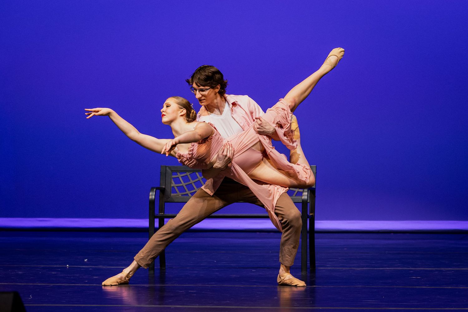 Two dancers perform a contemporary duet on stage with dramatic blue lighting and graceful movements.