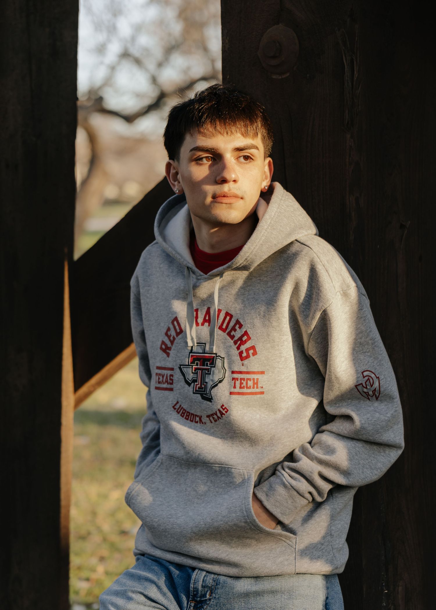 Someone wearing a gray Texas Tech collegiate hoodie and jeans poses outdoors in natural lighting.