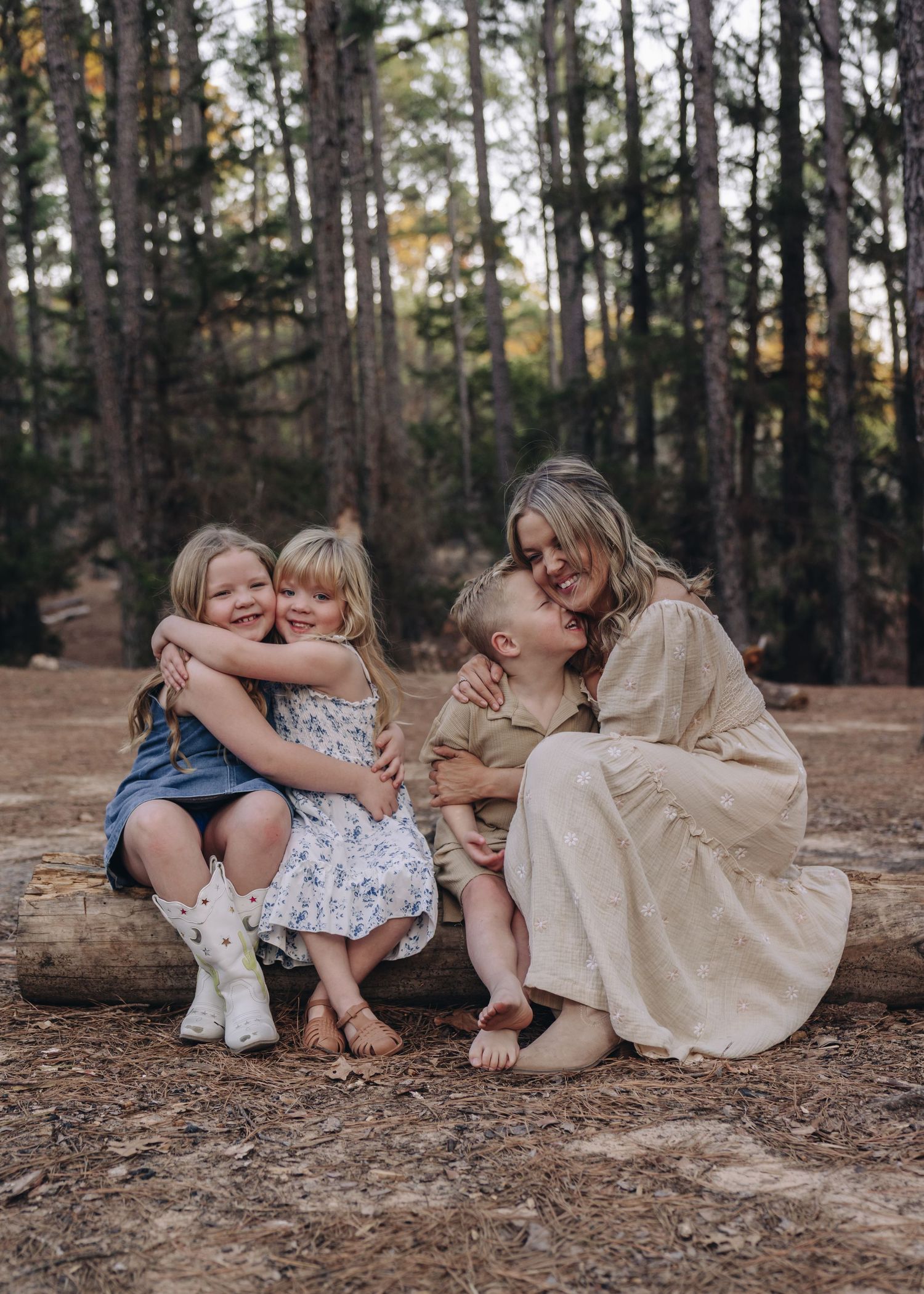 A joyful candid moment of family bonding while sitting together on a fallen log in a peaceful forest setting.