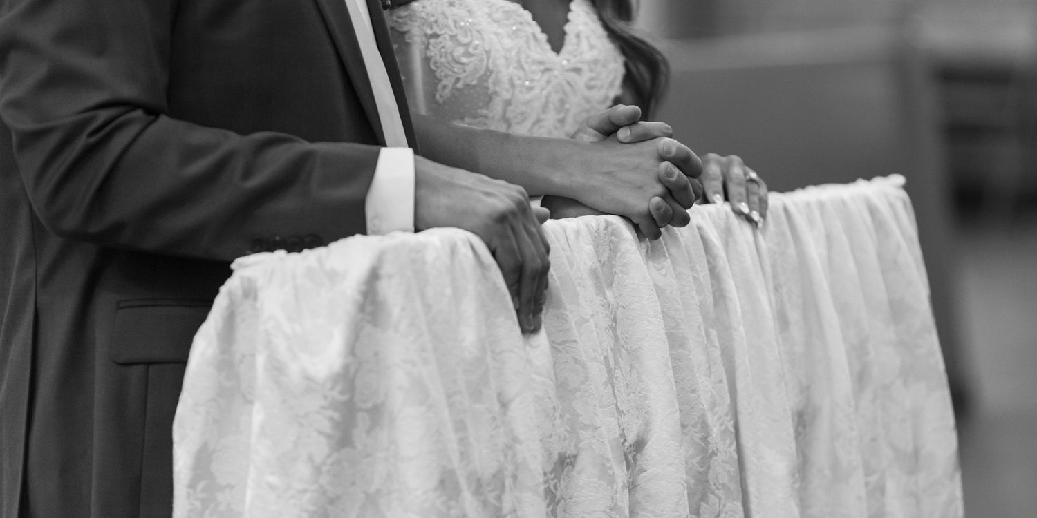 Black and white photo of bride and groom cutting wedding cake at elegant reception ceremony.