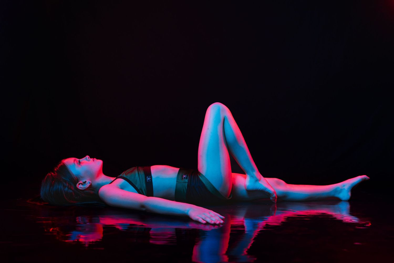 Artistic nude silhouettes in red and blue lighting create a dramatic 3D anaglyph effect against a black background.